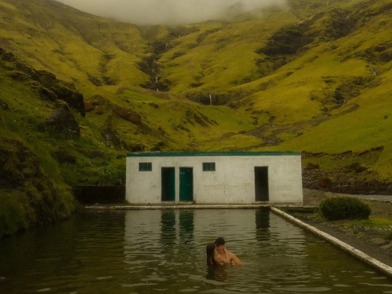 a couple swimming in a pool along the south coast of Iceland after their elopement