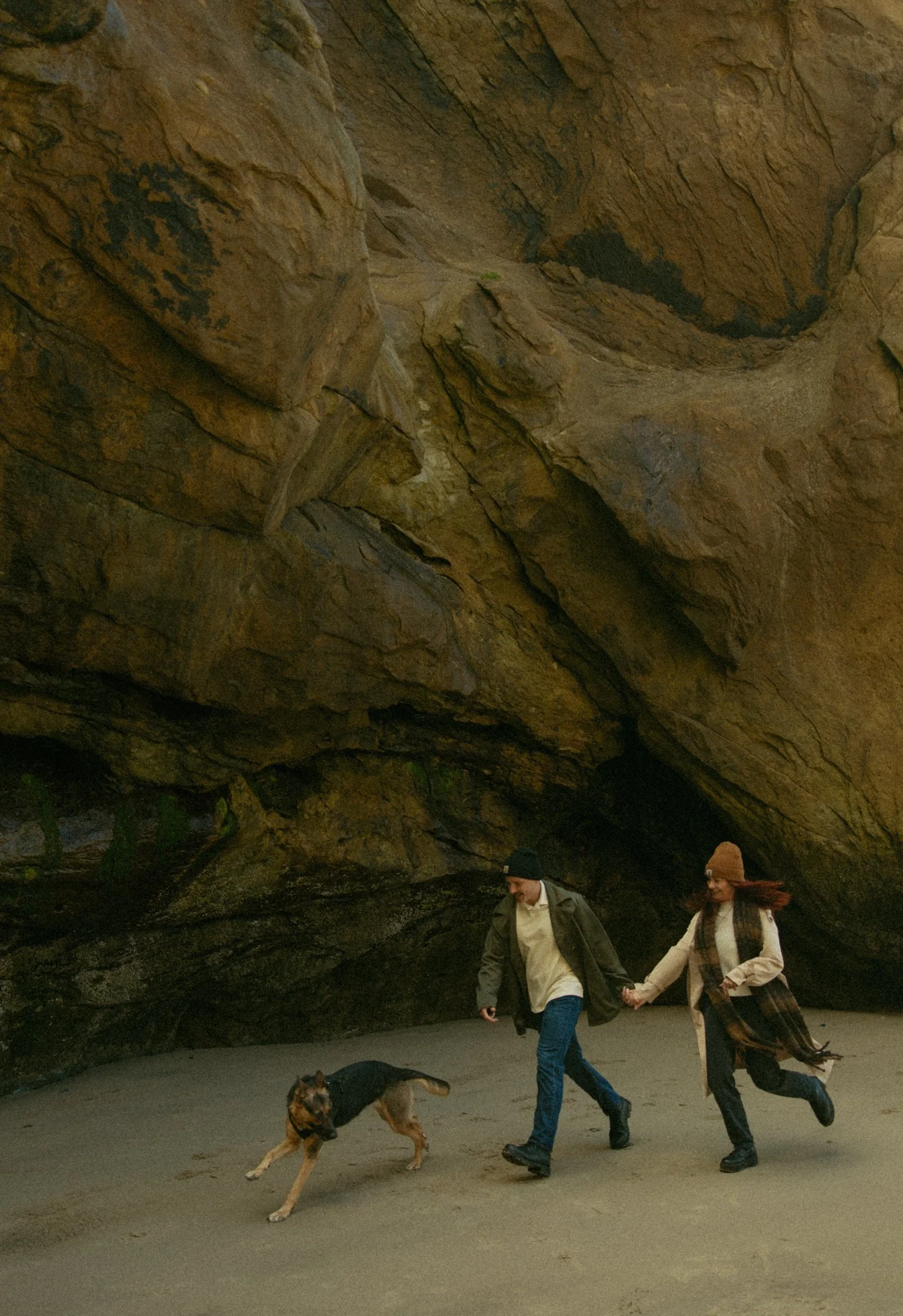 couple running with their dog on Hug Point Beach in Oregon