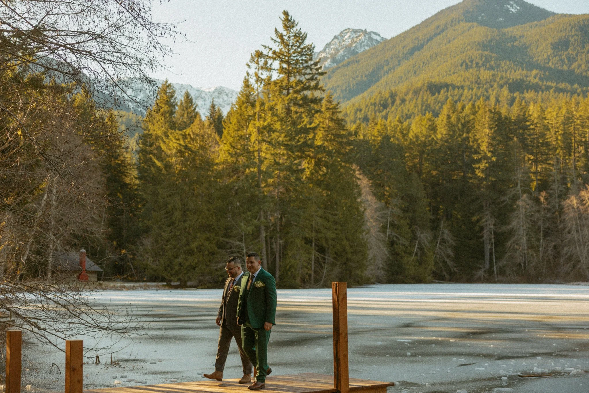 a LGBTQ+ elopement couple standing on the boat dock of a frozen lake on their elopement day