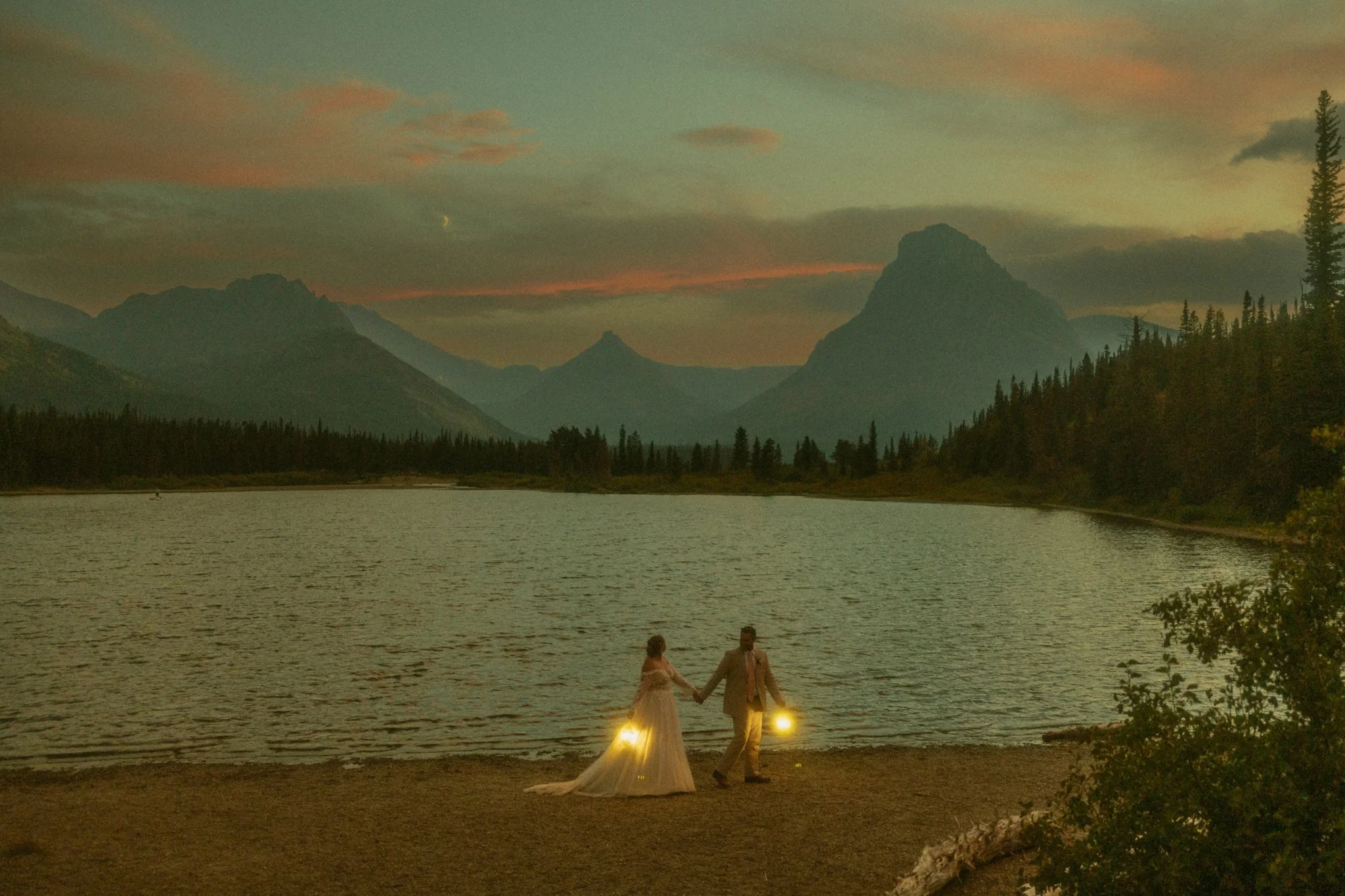 elopement couple walking along lakeshore in Glacier National Park after sun down