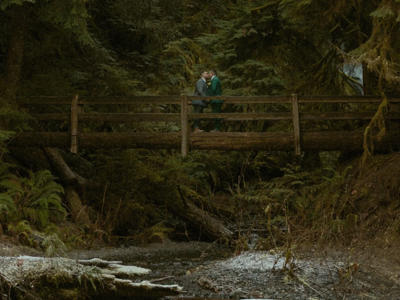 couple kissing on bridge in Washington forest