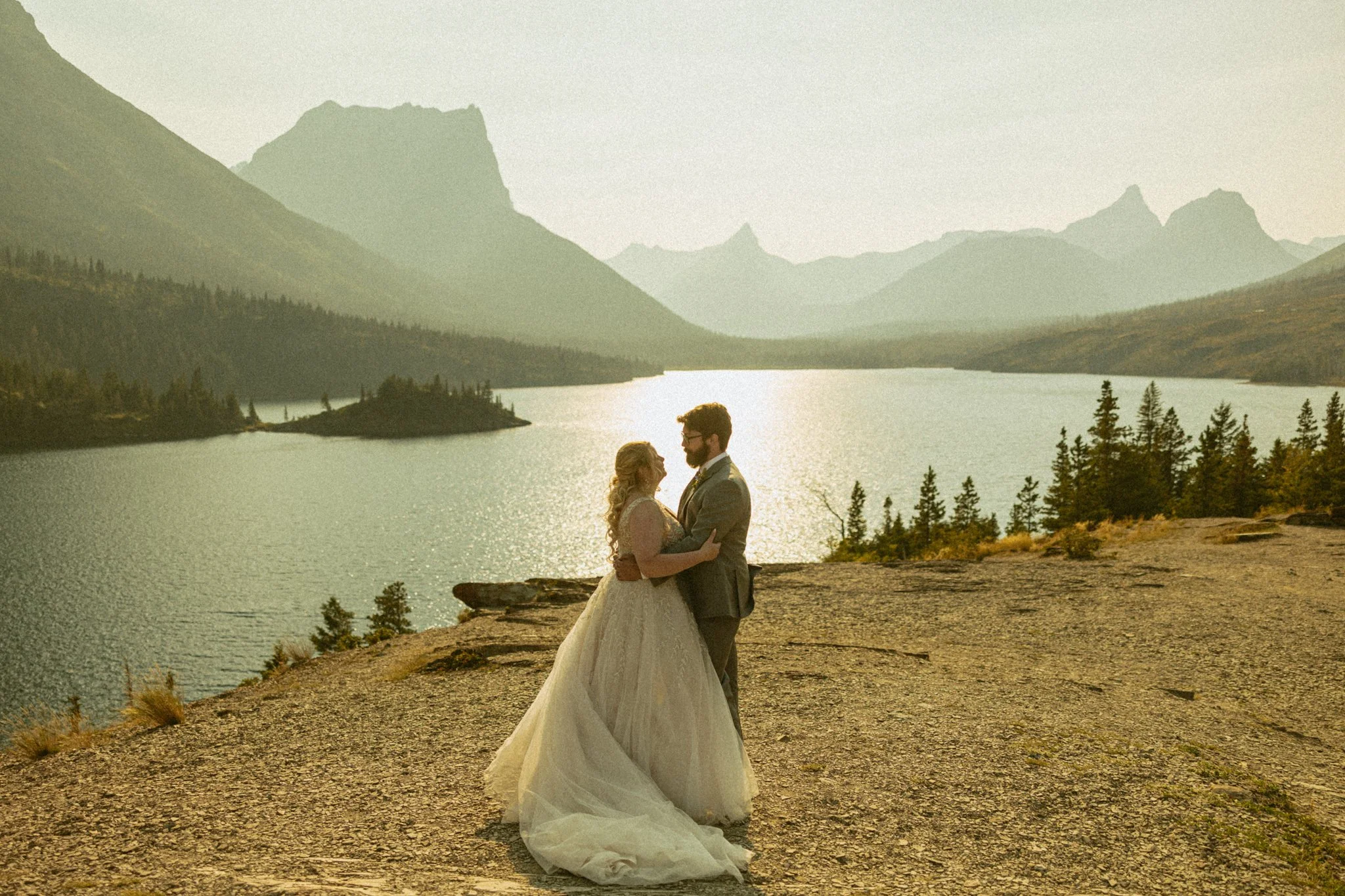 couple eloping on rocky cliff edge overlooking a lake and mountains in Montana's Glacier National Park