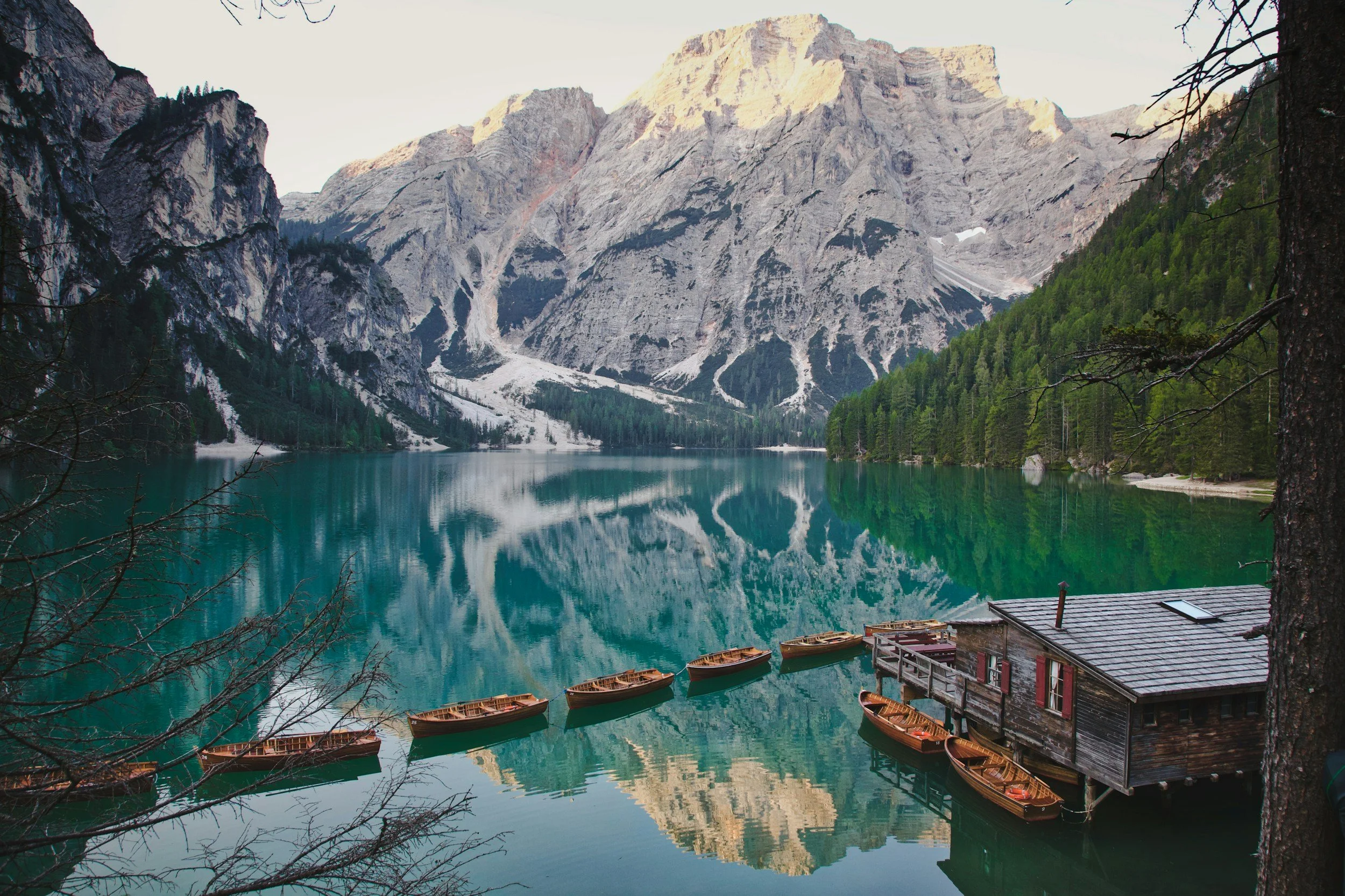 a landscape photo of the canoes resting on Lago di Braies at sunrise in the Dolomites