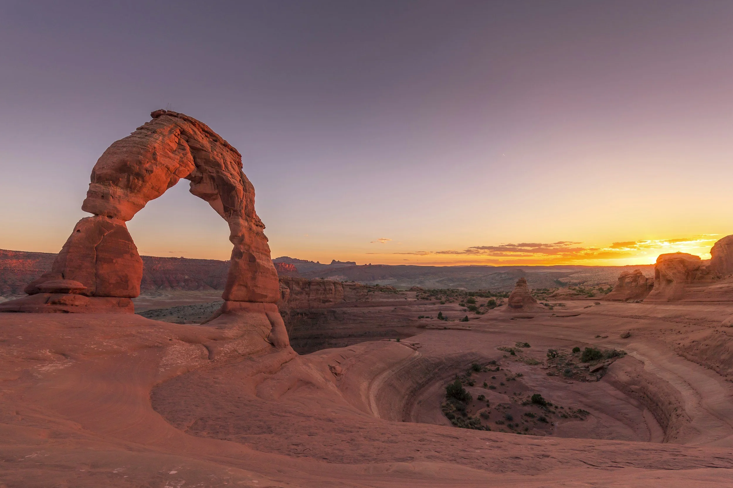 a landscape photo of Delicate Arch in Arches National Park at sunset