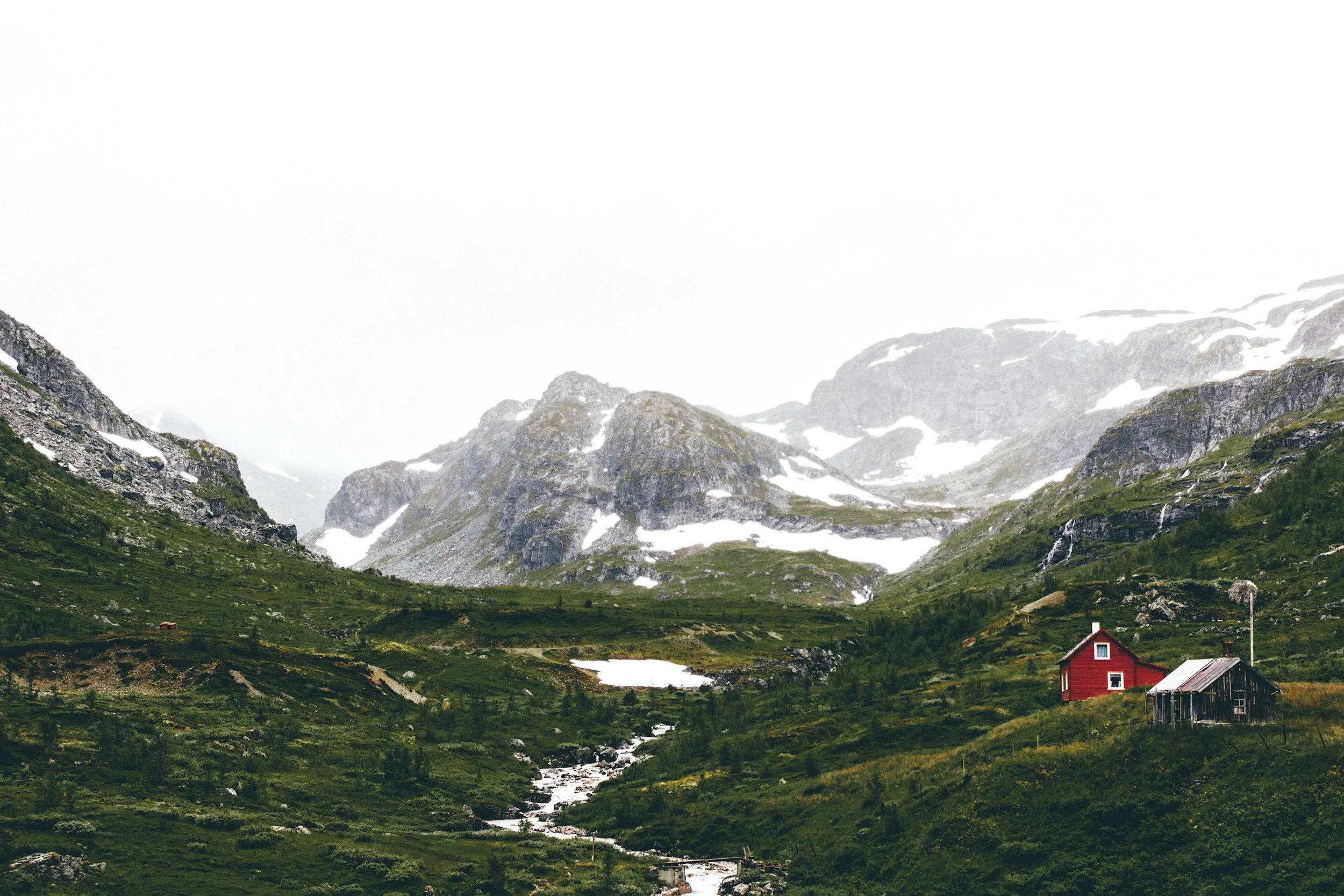 a landscape of mountains and a few small cabins in Norway