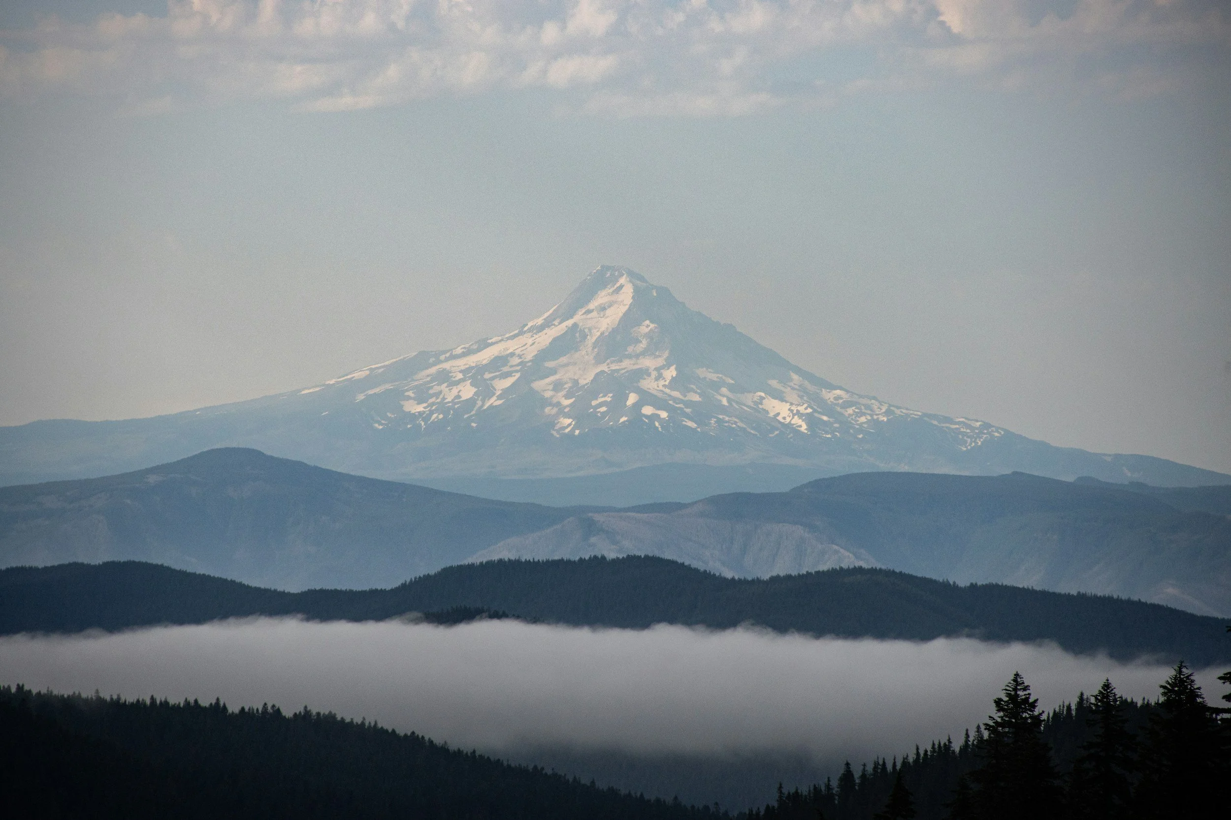 a landscape of Mt Hood surrounded by lower peaks and clouds