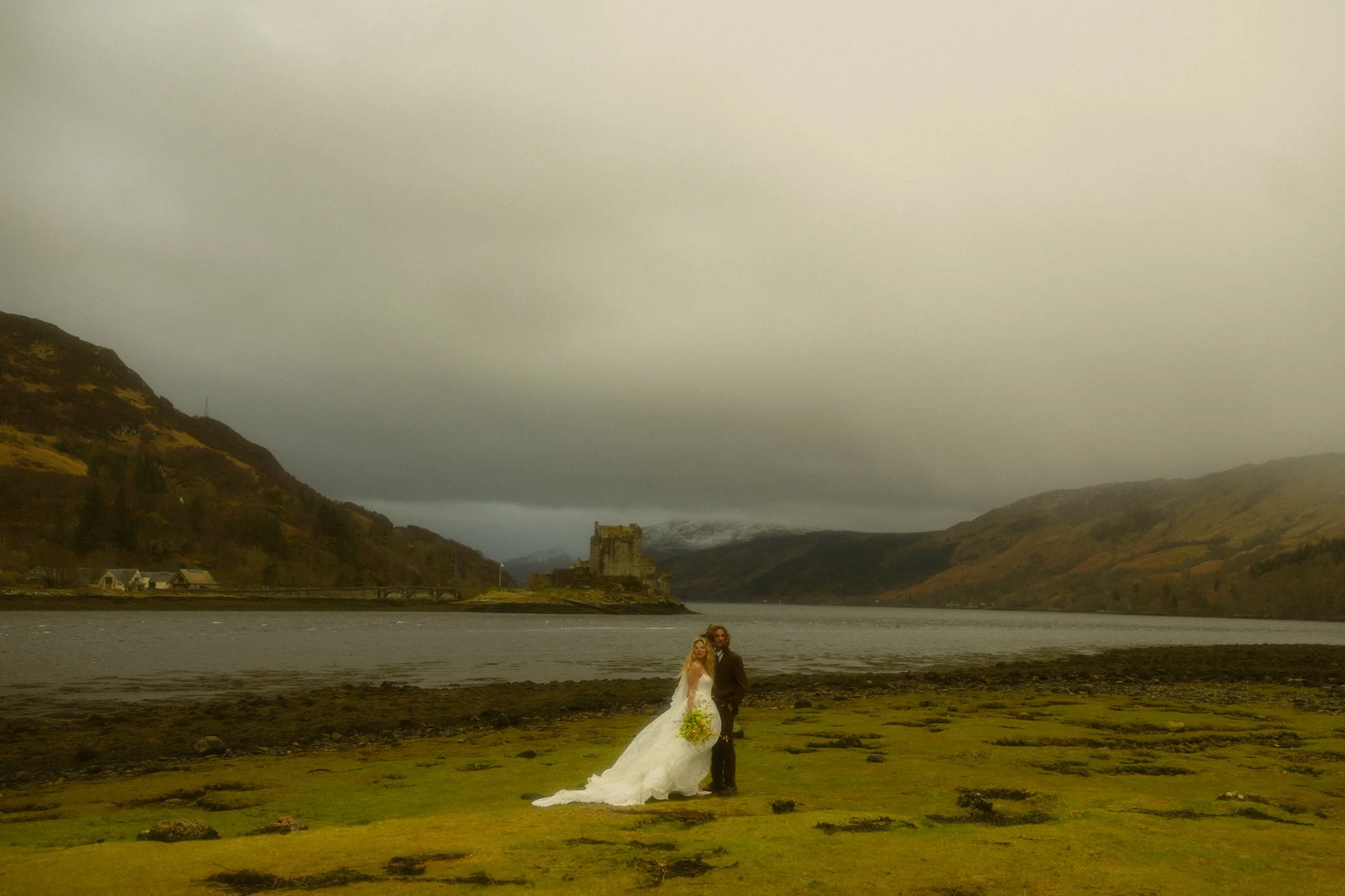 a couple getting married with Eilean Donan Castle in the background in the Scottish Highlands
