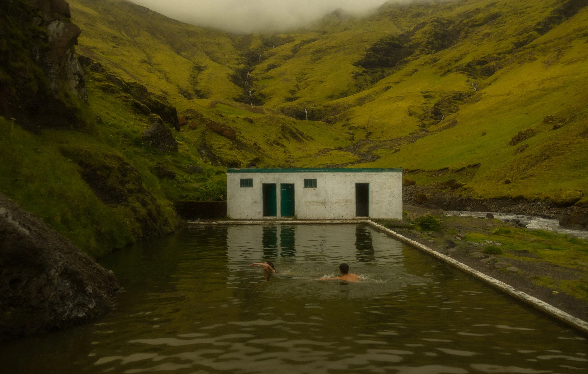 a couple swimming in a remote mountain pool in Iceland after their elopement
