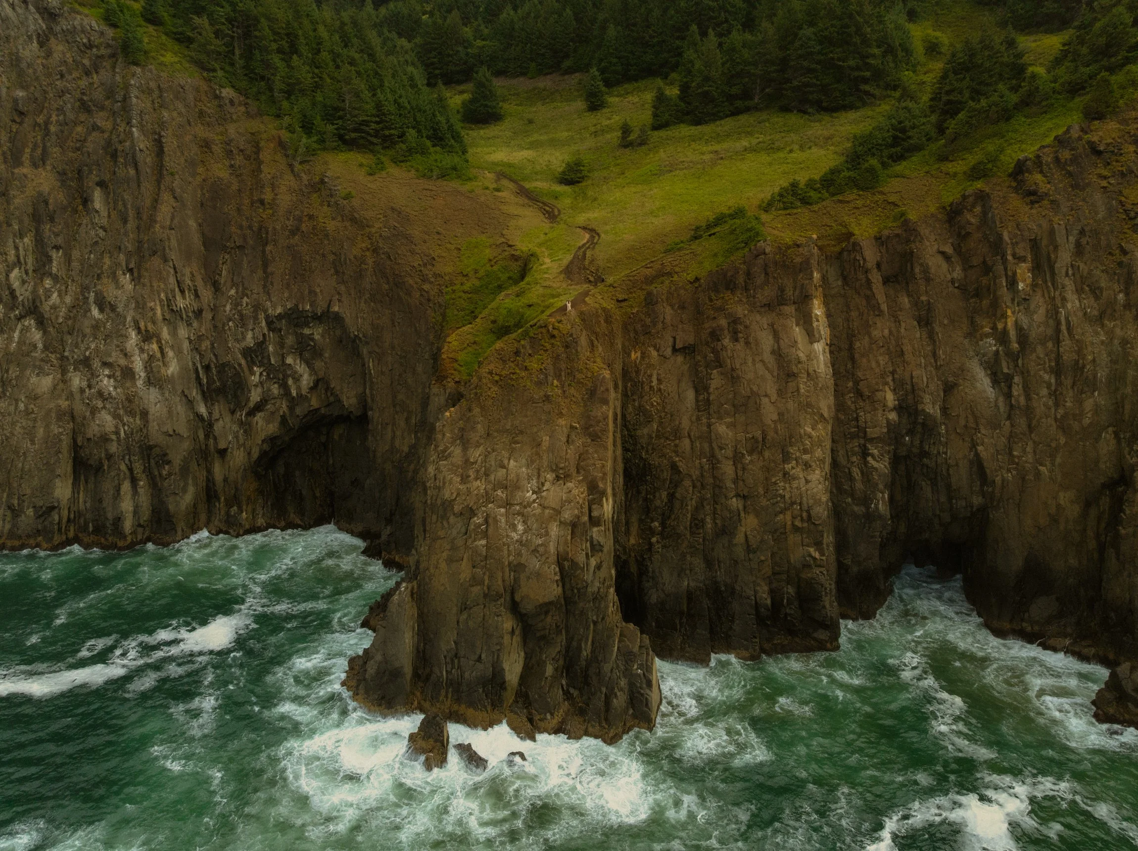 a couple eloping along a rugged coastal cliff edge on the Oregon Coast