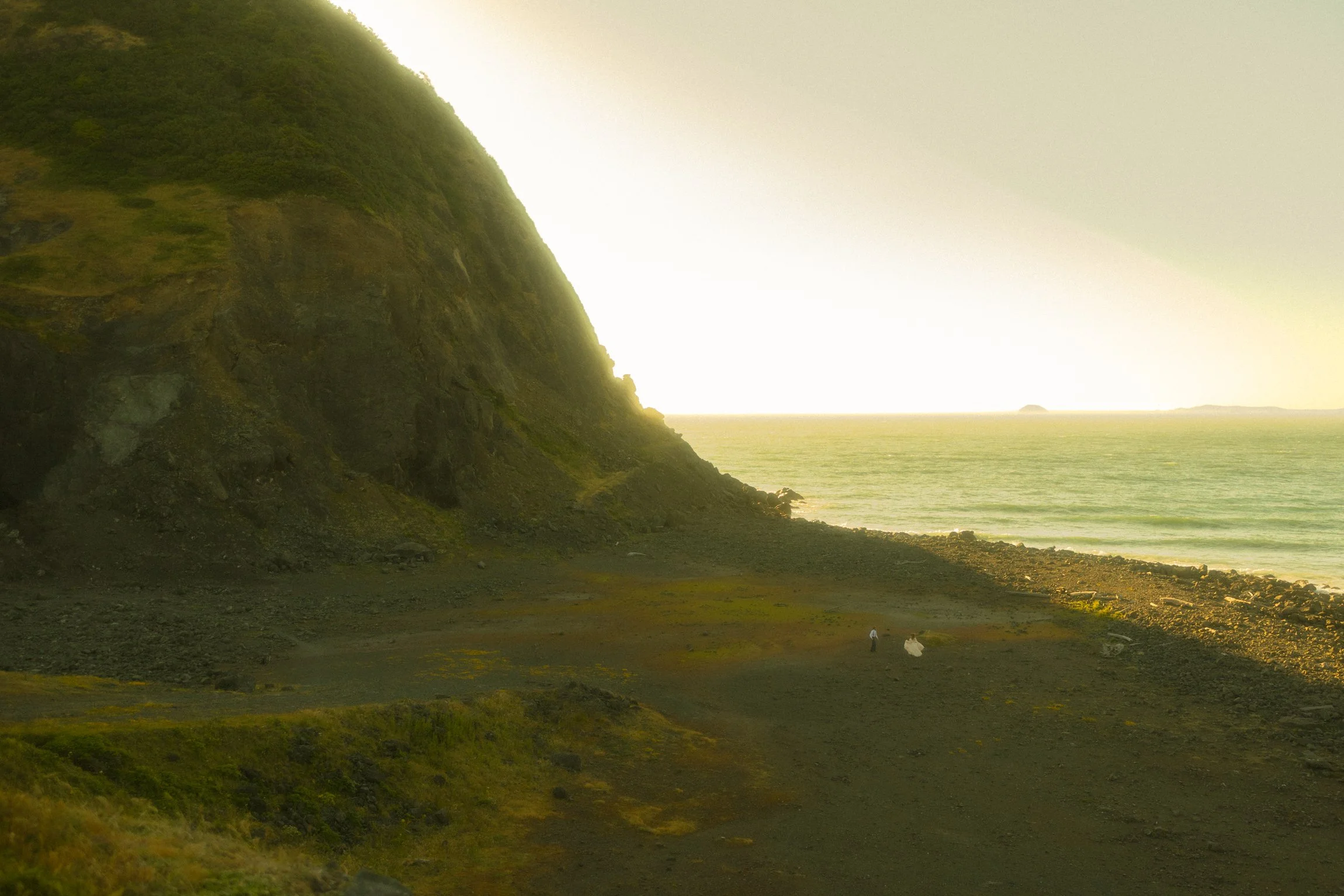 an elopement couple running on a black sand beach in Oregon