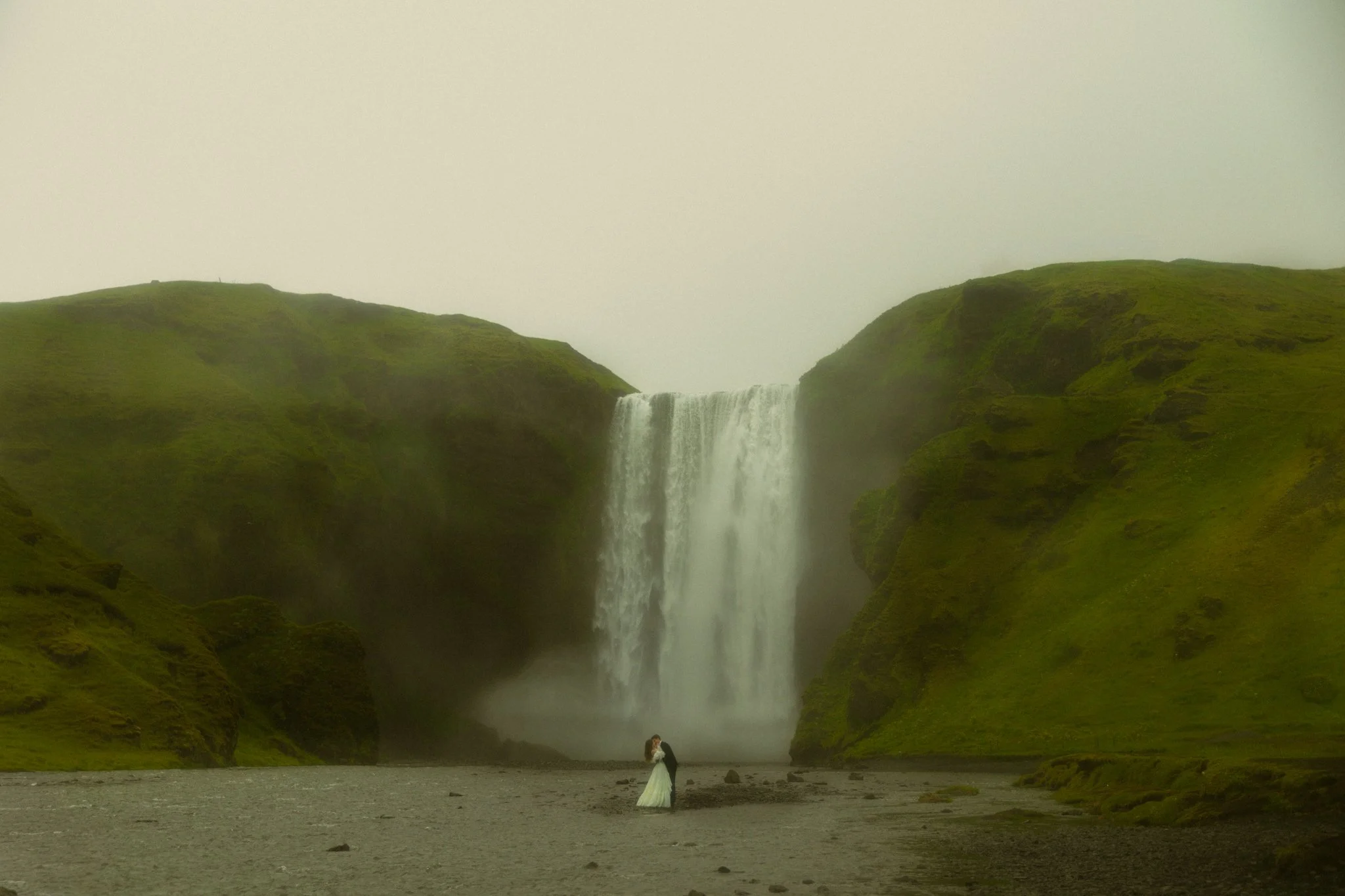 an elopement couple kissing under Skogafoss in Iceland