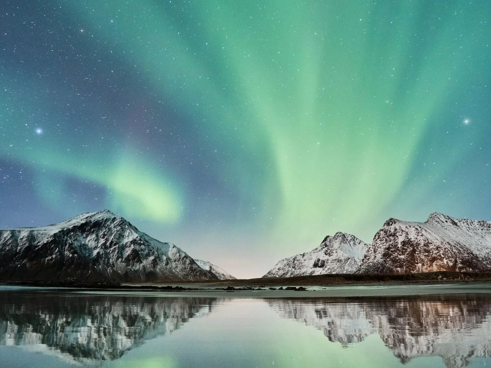 a landscape of northern lights above snowy mountains and a lake