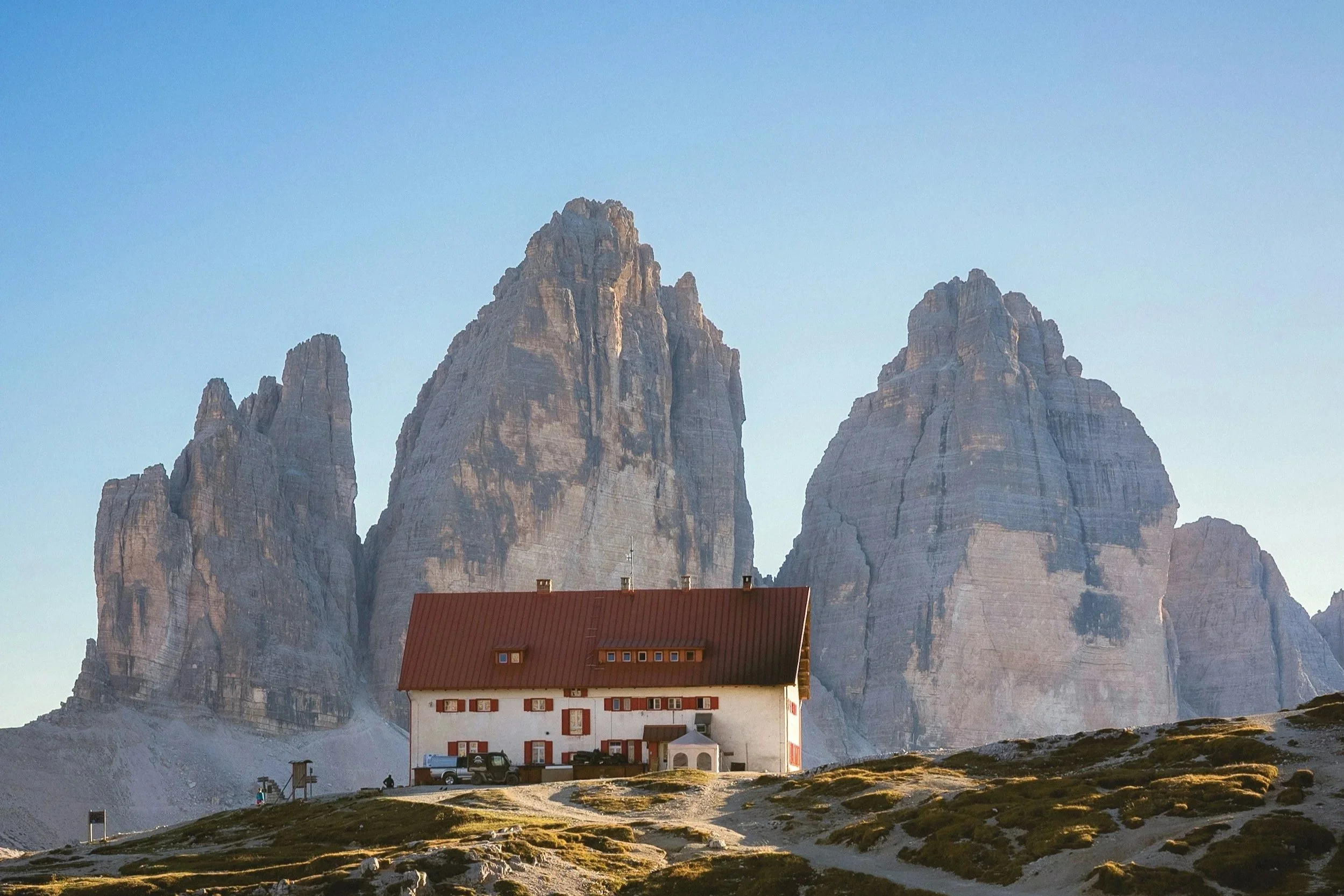 a photo of a mountain hut with the mountains behind it in the Dolomites