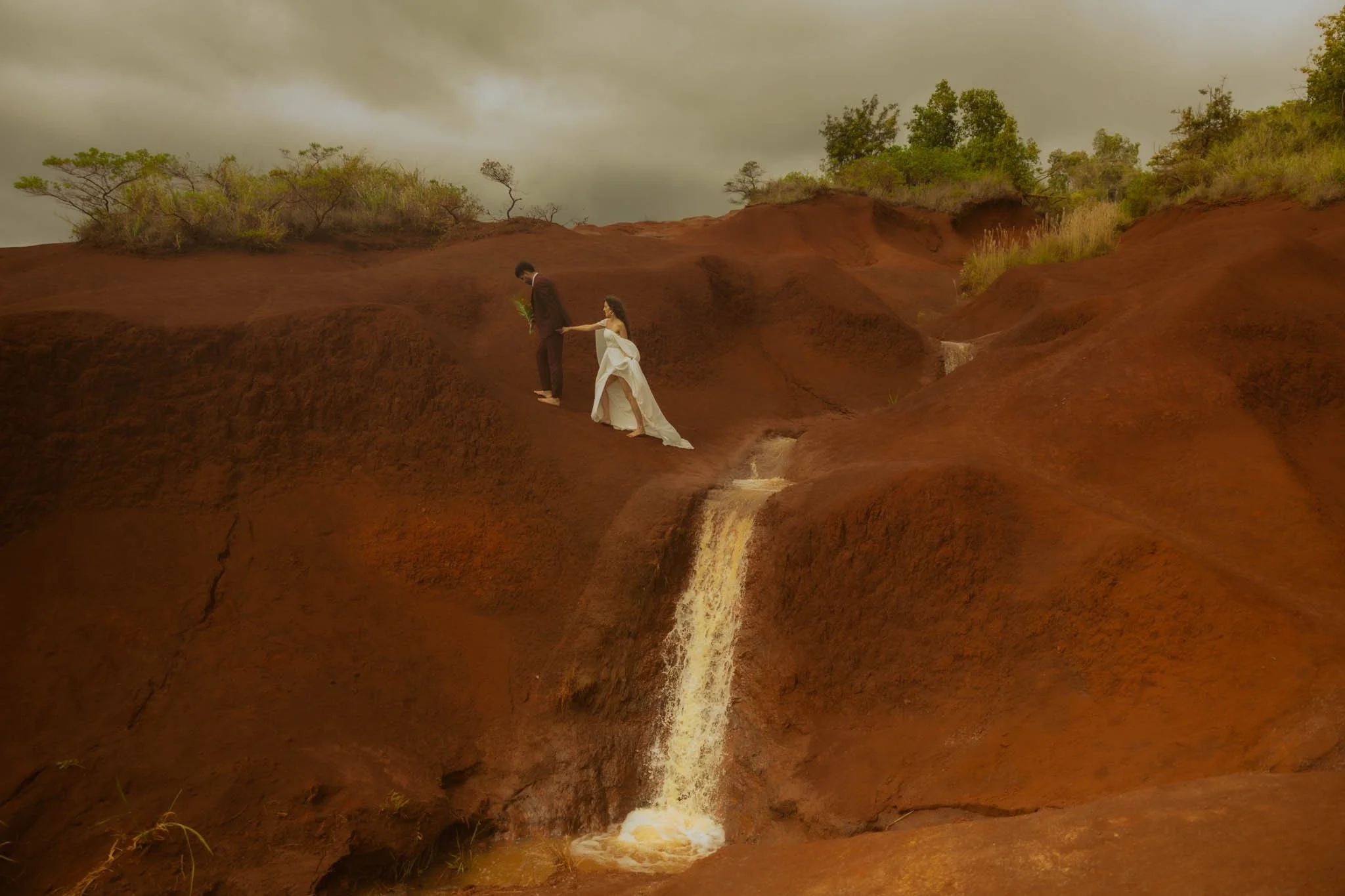 a wedding couple walking among the Red Dirt Waterfall in Kauai, Hawaii