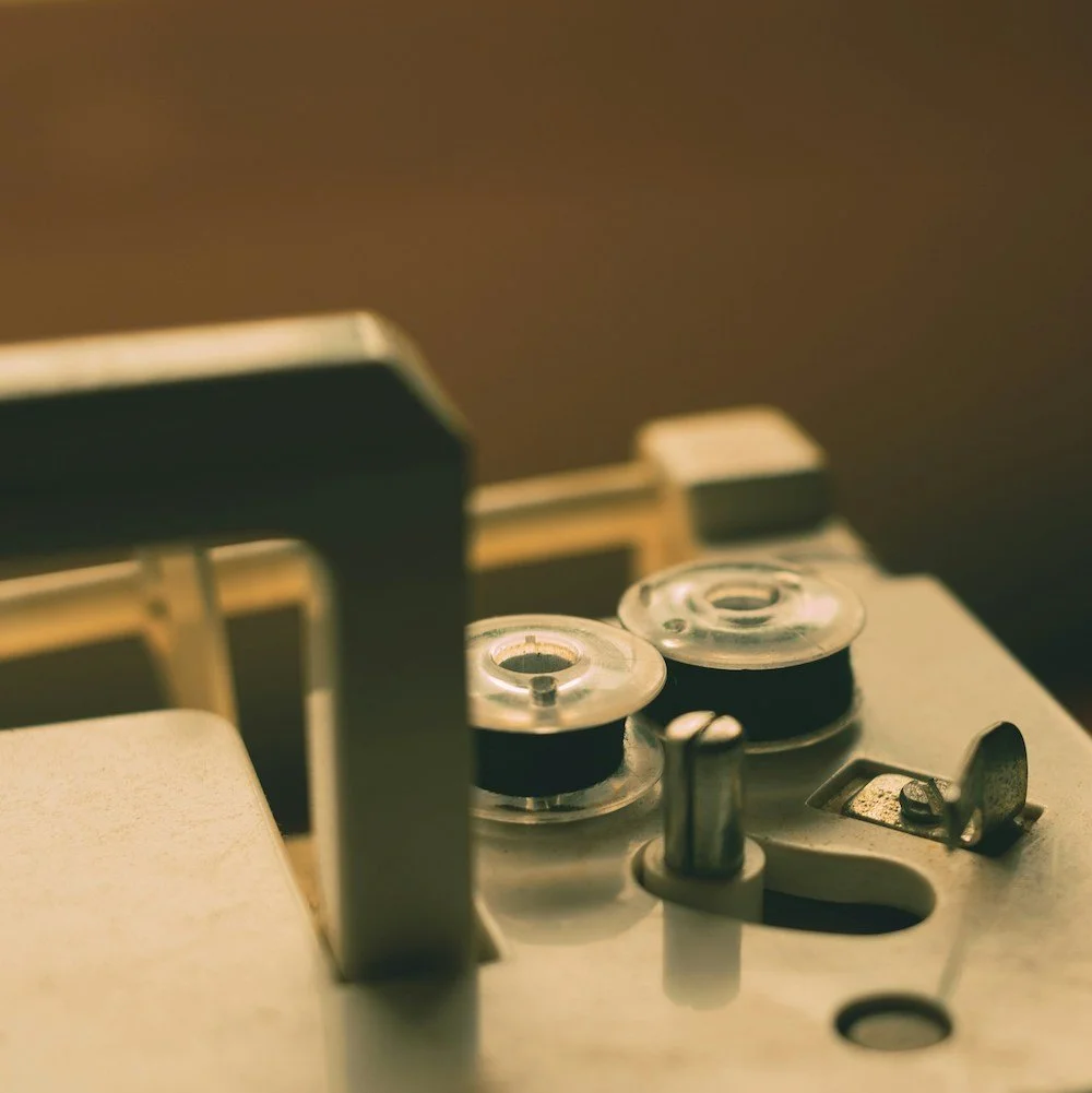 Close-up of a vintage reel-to-reel tape recorder showing two tape spools and control knobs.
