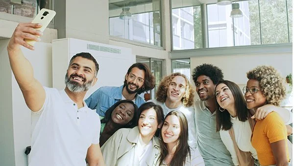 Group of diverse smiling people taking a selfie together indoors.