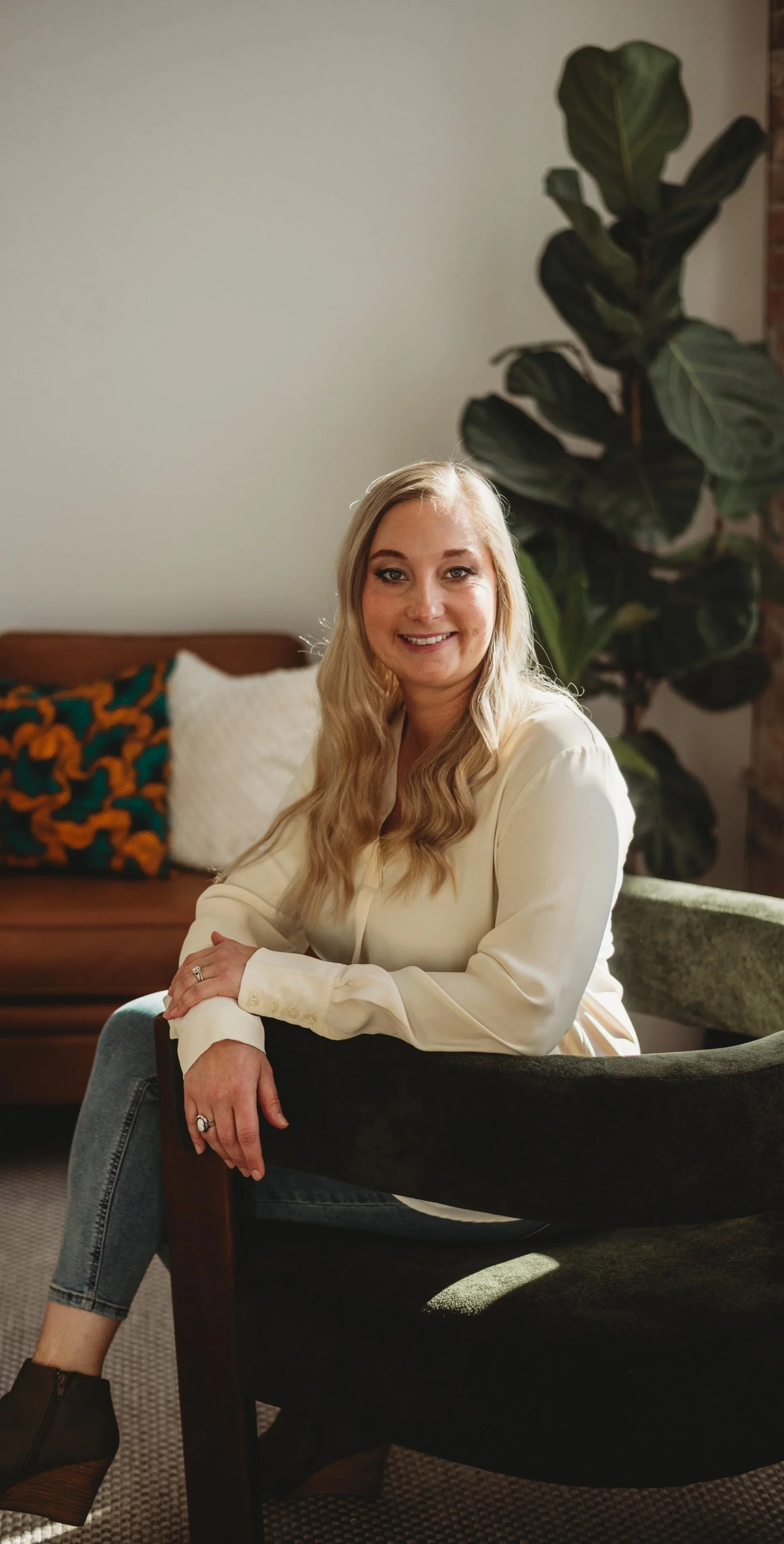 Kelsey Mammen, therapist, sitting on her office chair in Colorado, smiling at the camera