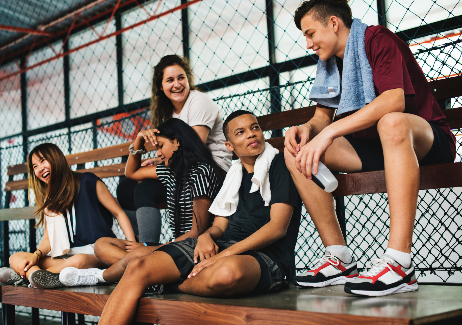 group of students sitting in a gym after training representing sport psychology workshops and team support