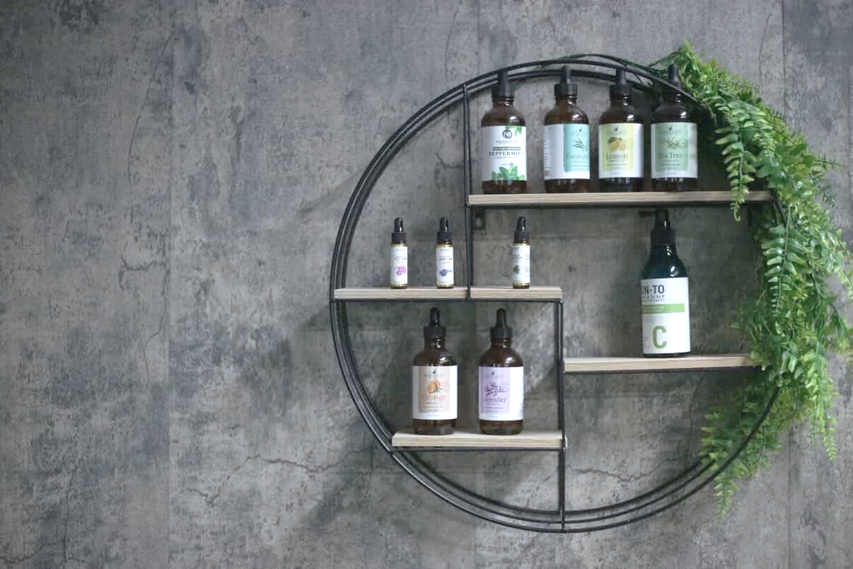 Wall-mounted circular metal shelf with bottles and plants on a concrete wall that shows the tranquility of the head spa experience