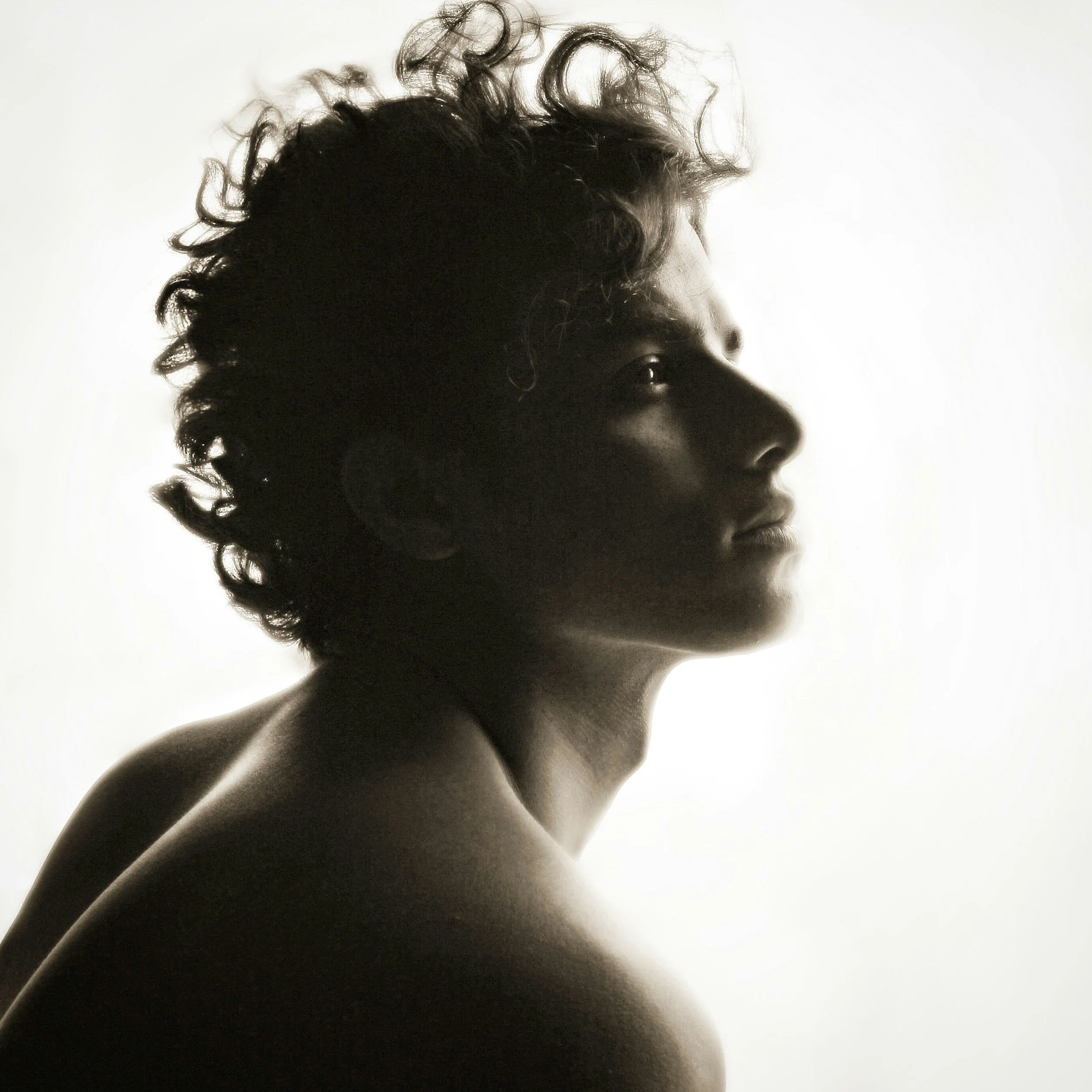 A black and white side profile of a young woman with curly hair looking to the right.