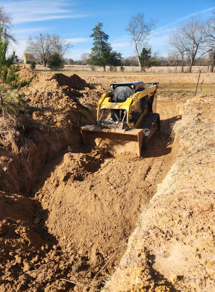 Small yellow bulldozer clearing dirt in a construction site with trees in the background.