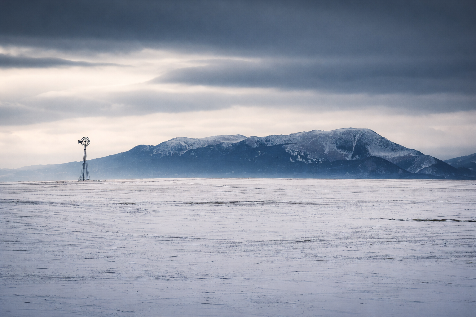 "The Long Quiet"
Snow stretches beyond purpose, a landscape emptied of urgency. The mountains remain, but even they feel distant—like memory more than place.
