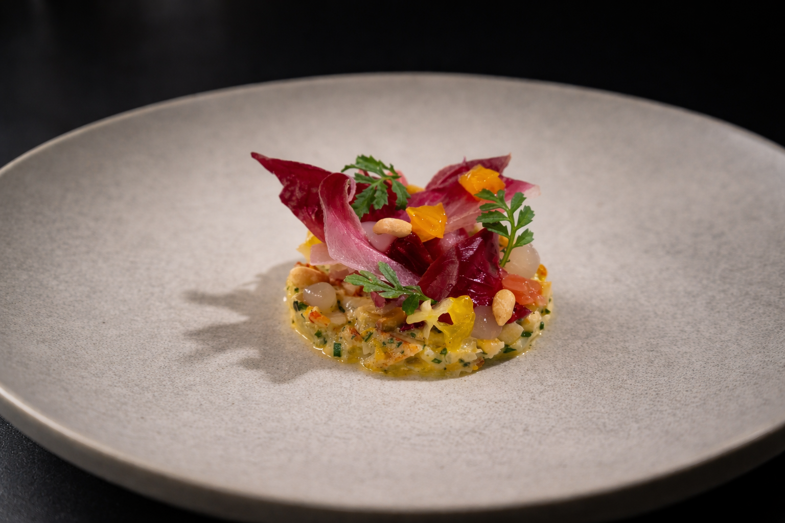 A gourmet dish featuring a colorful assortment of vegetables, herbs, and nuts artfully arranged on a large, light-colored ceramic plate.