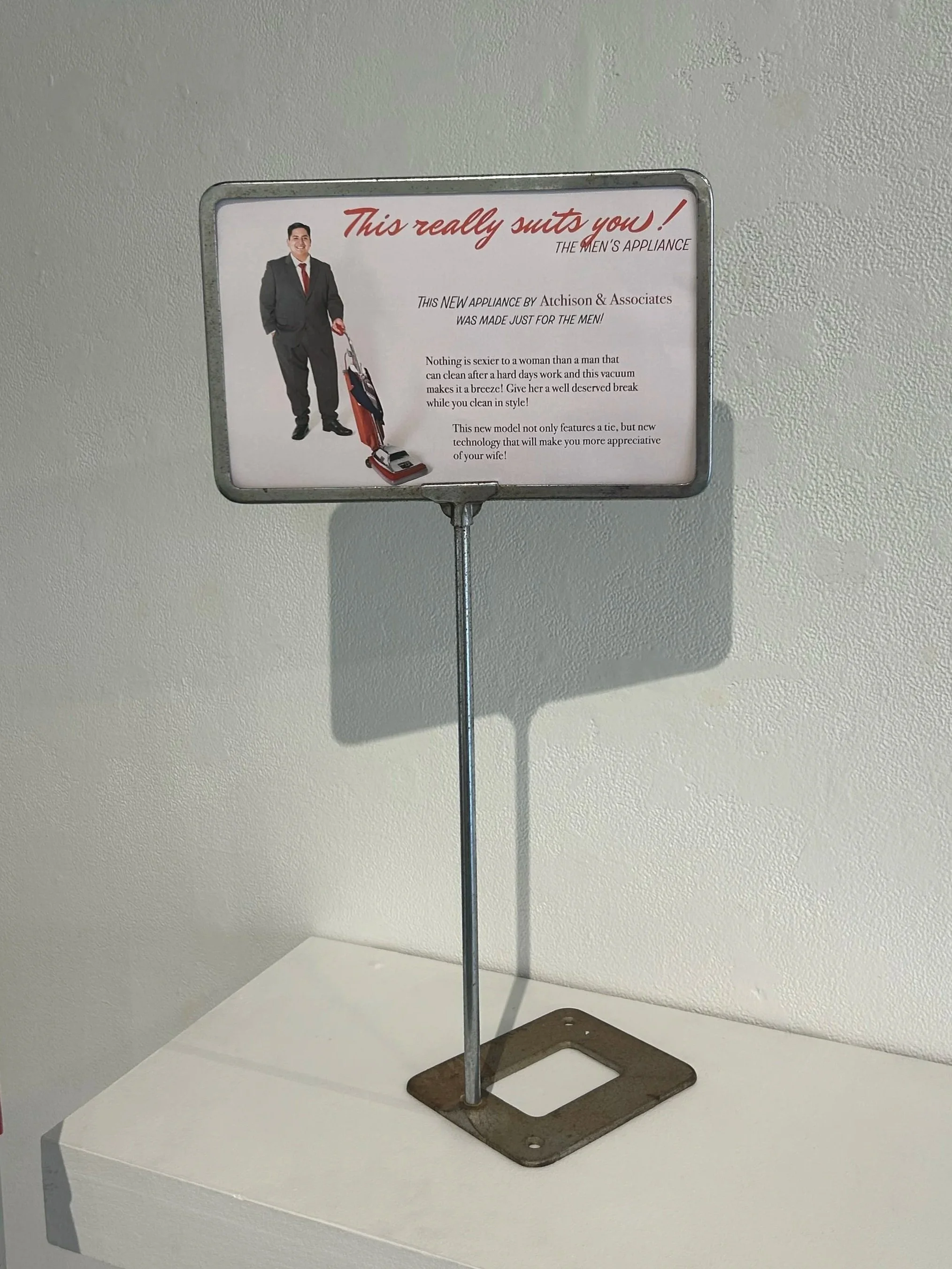 "This really suits you!" signage, 40in x 16in x 14in, Vacuum, fabric, thread, and button, 2025- 2026
