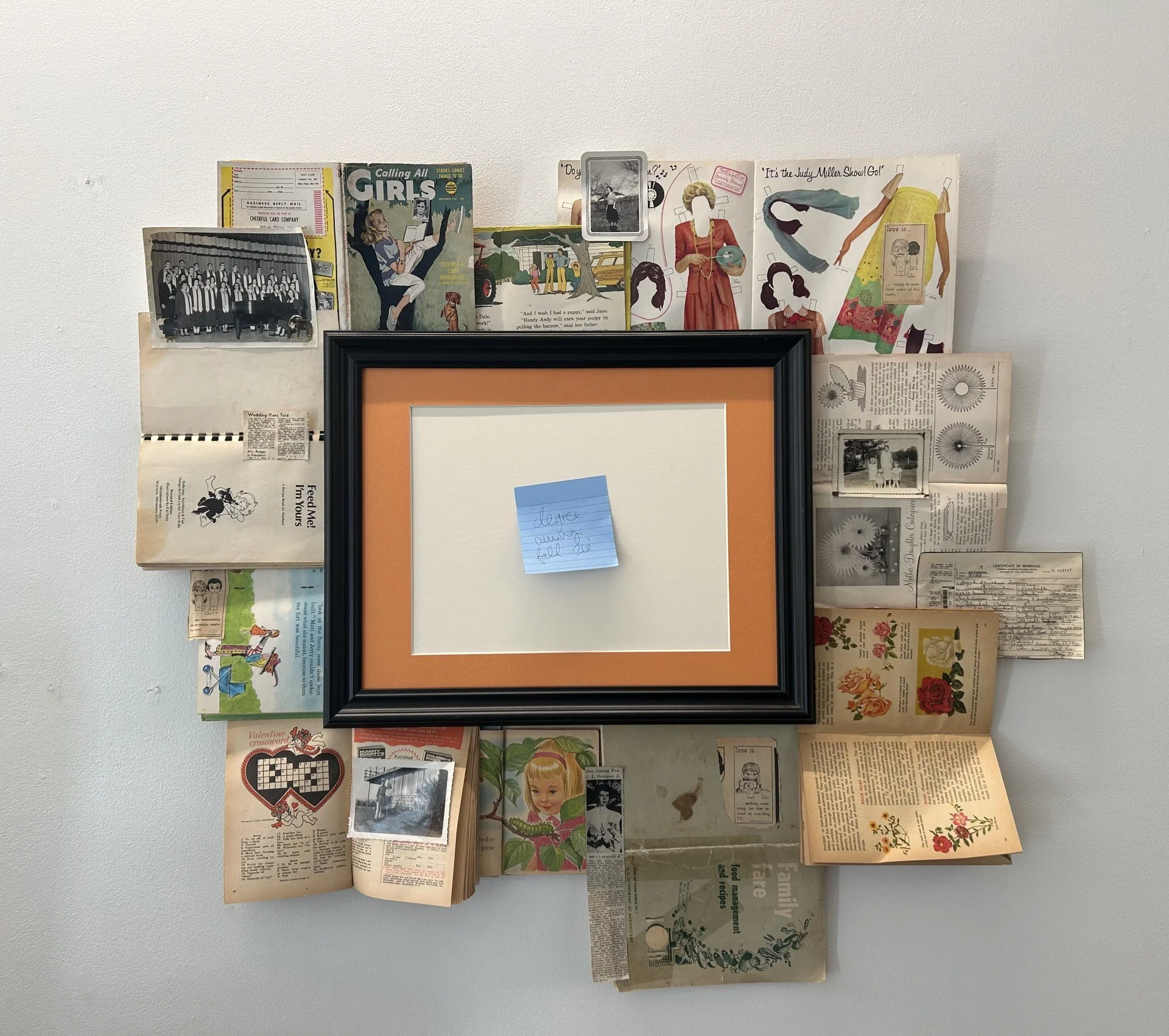 "MRS. Degree", 2026, books, photographs, text, frame, sticky note.