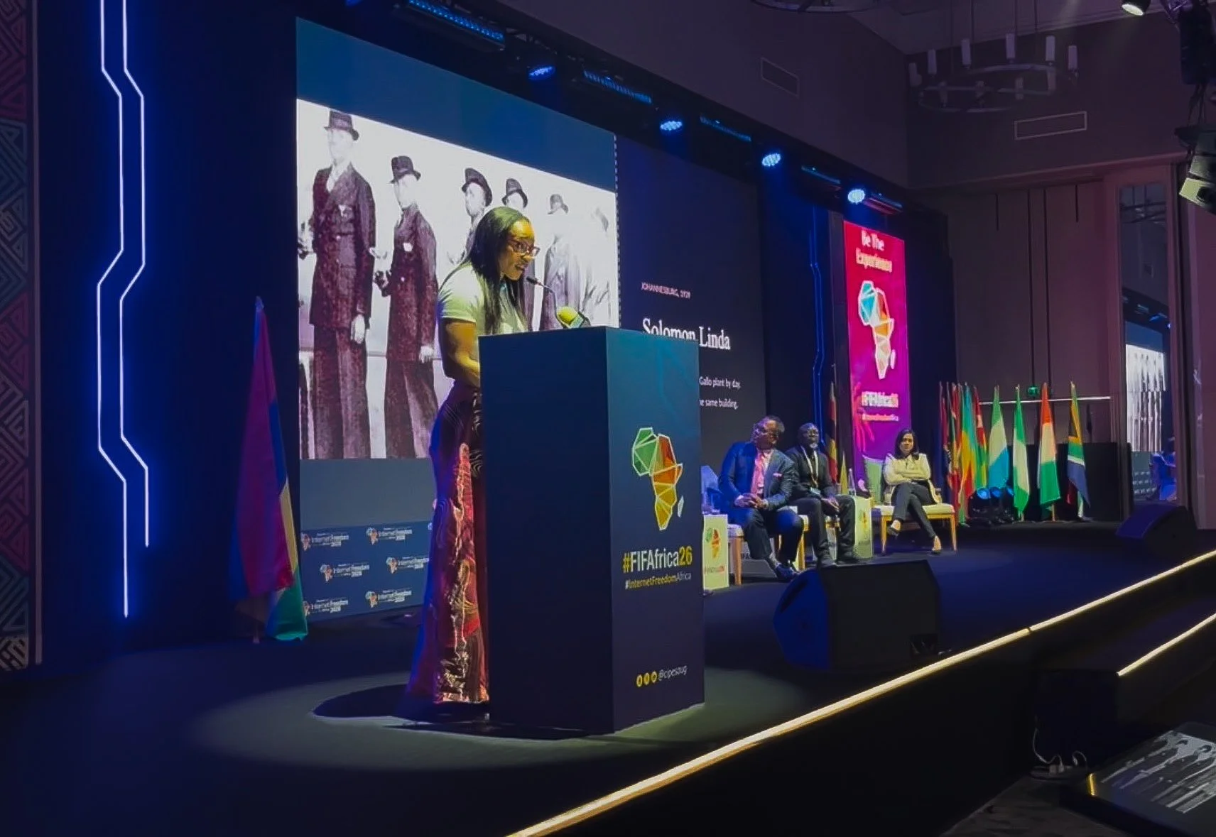 Barbra Okafor at the podium in a spotlight, giving the opening keynote on the main stage of the Forum on Internet Freedom in Africa