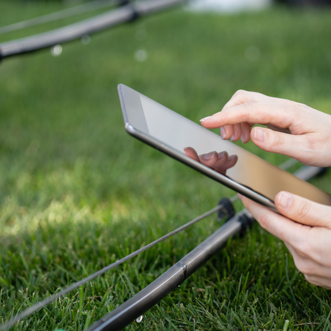 A person using a smartphone outdoors on a grassy field, with part of a golf club visible in the background.