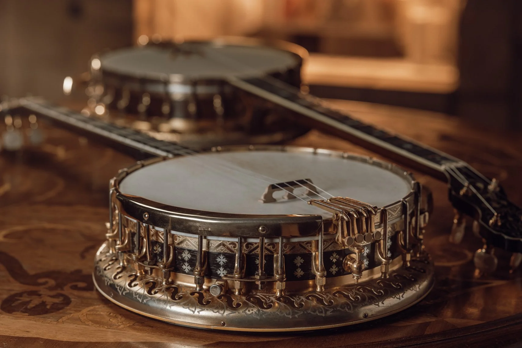 Close-up of a vintage banjo with metal and wooden details on a wooden table, with a blurred background.