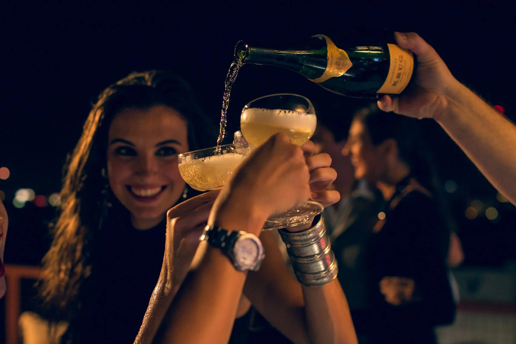 People celebrating with glasses of champagne at night.
