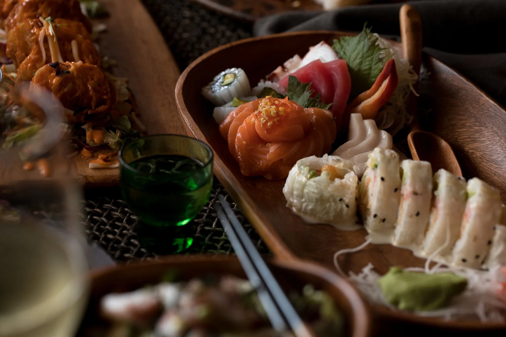 Assorted Japanese sushi and sashimi on a wooden platter with soy sauce and chopsticks.