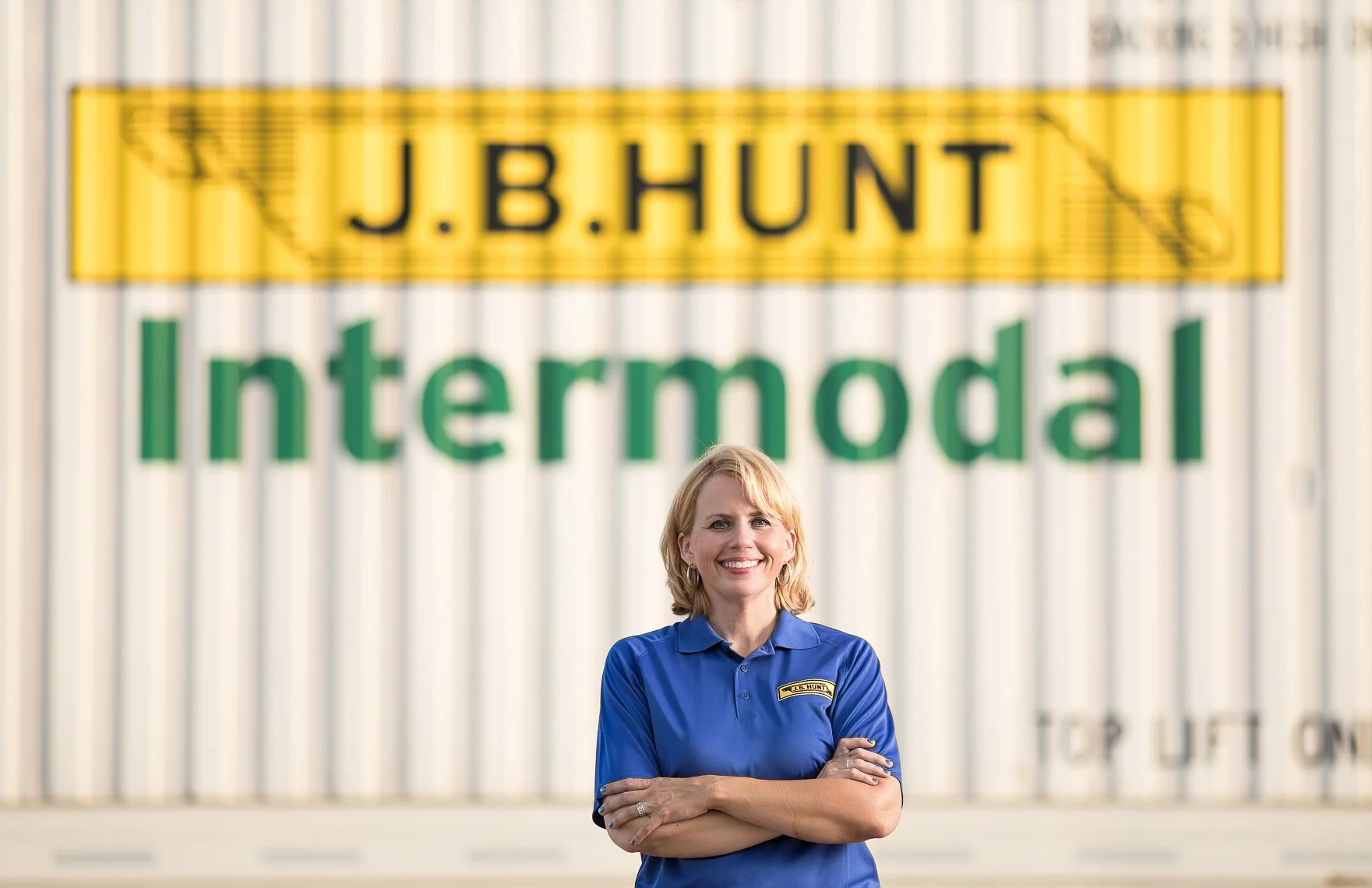 Woman in blue shirt standing in front of intermodal shipping containers with J.B. Hunt and intermodal signs