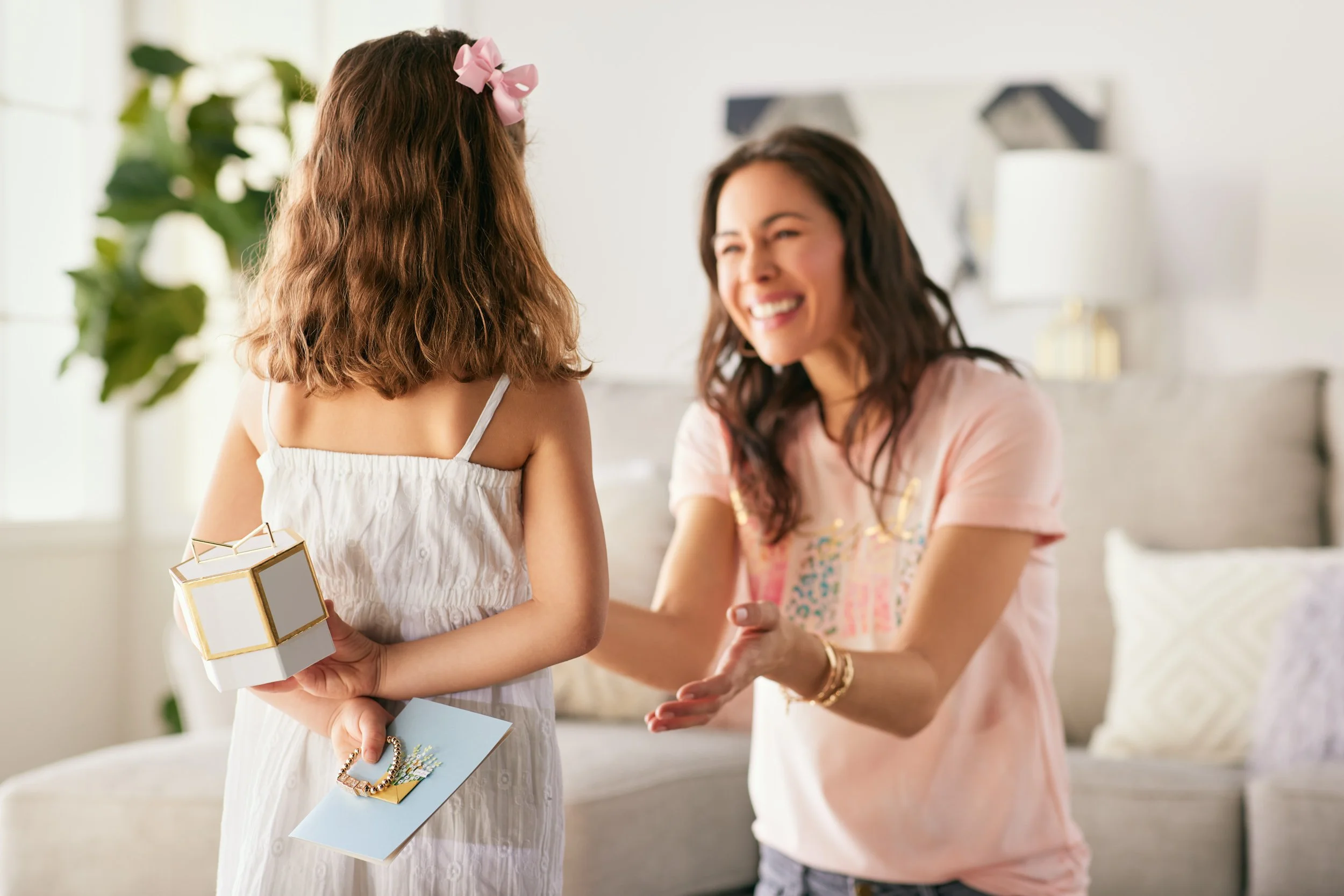 Two women exchanging gifts and smiling in a brightly lit living room