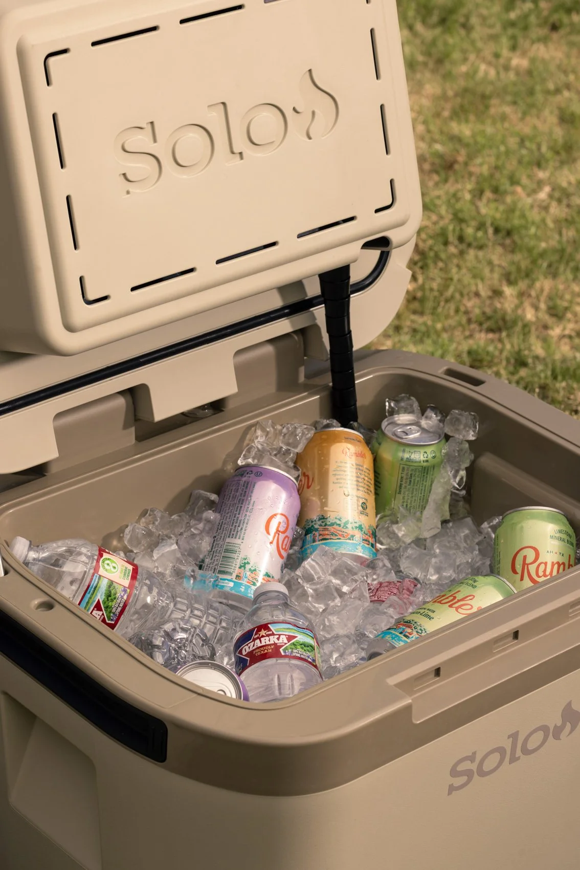 Open cooler filled with ice and various cans and bottles of drinks.
