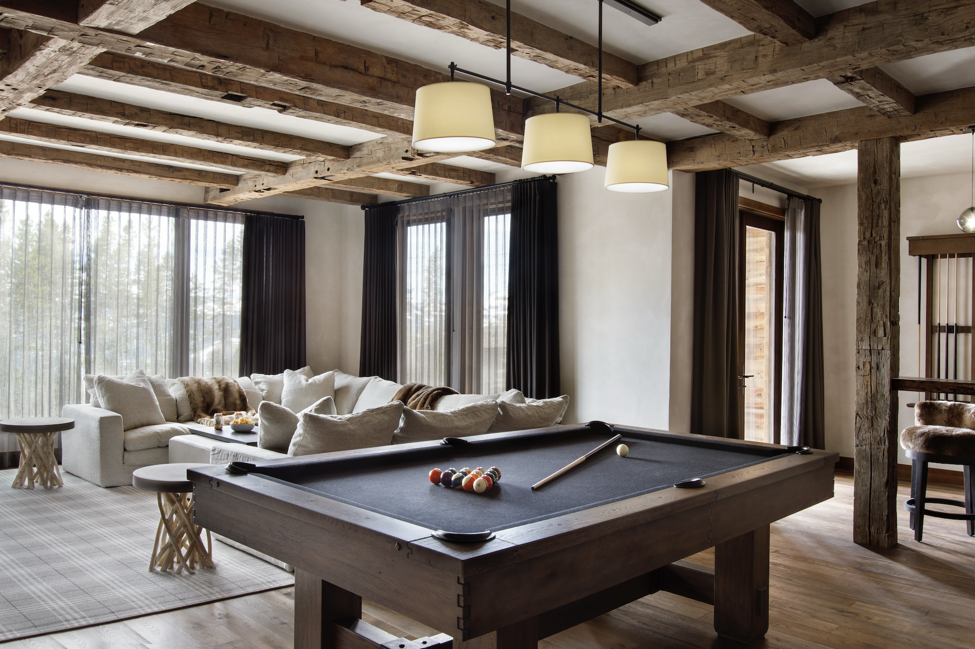 Recreation room with billiards table, lounge seating, and reclaimed timber ceiling.