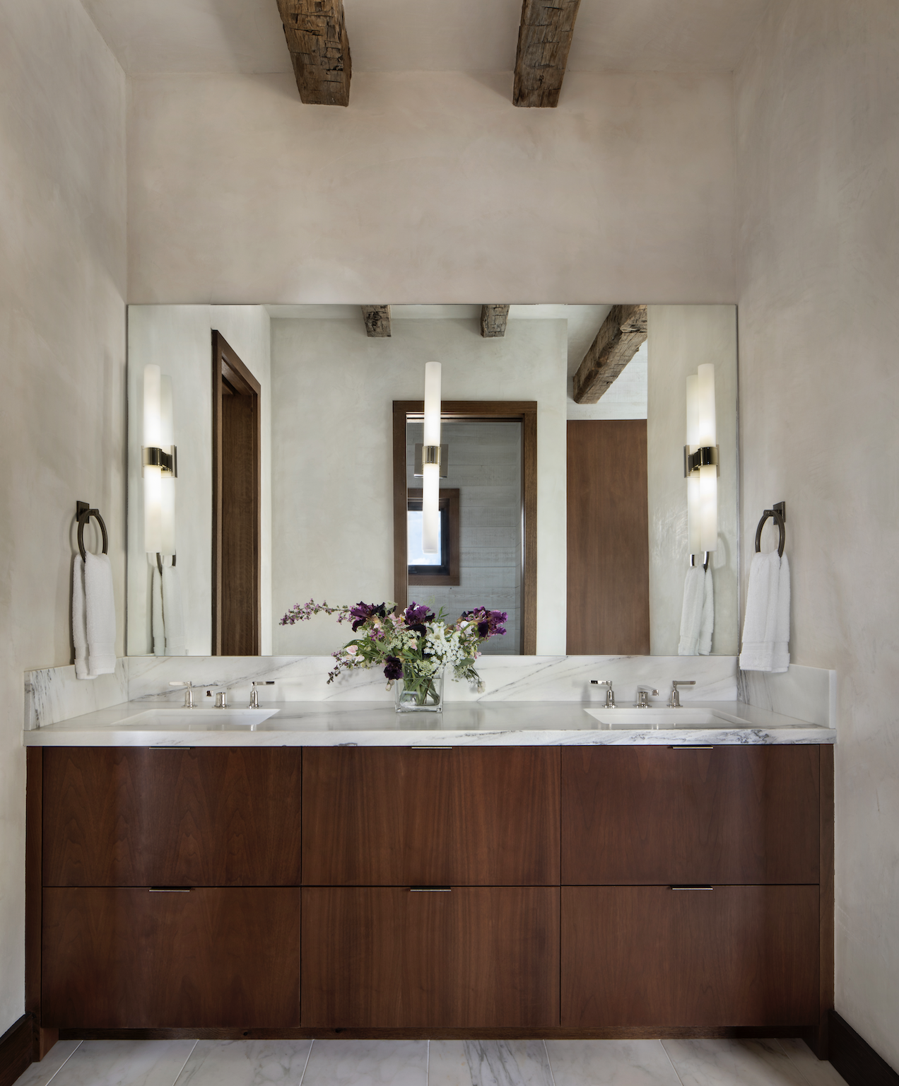 Double vanity with marble countertop, wood cabinetry, and large wall mirror in the master bathroom.