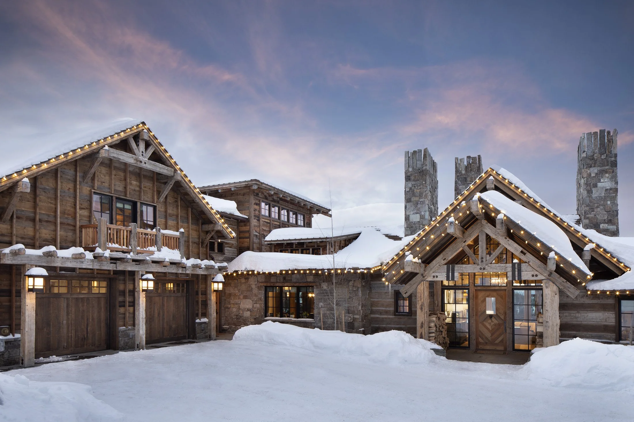 Timber and stone mountain lodge exterior with cedar shingle roof in winter at Moonlight Basin Montana