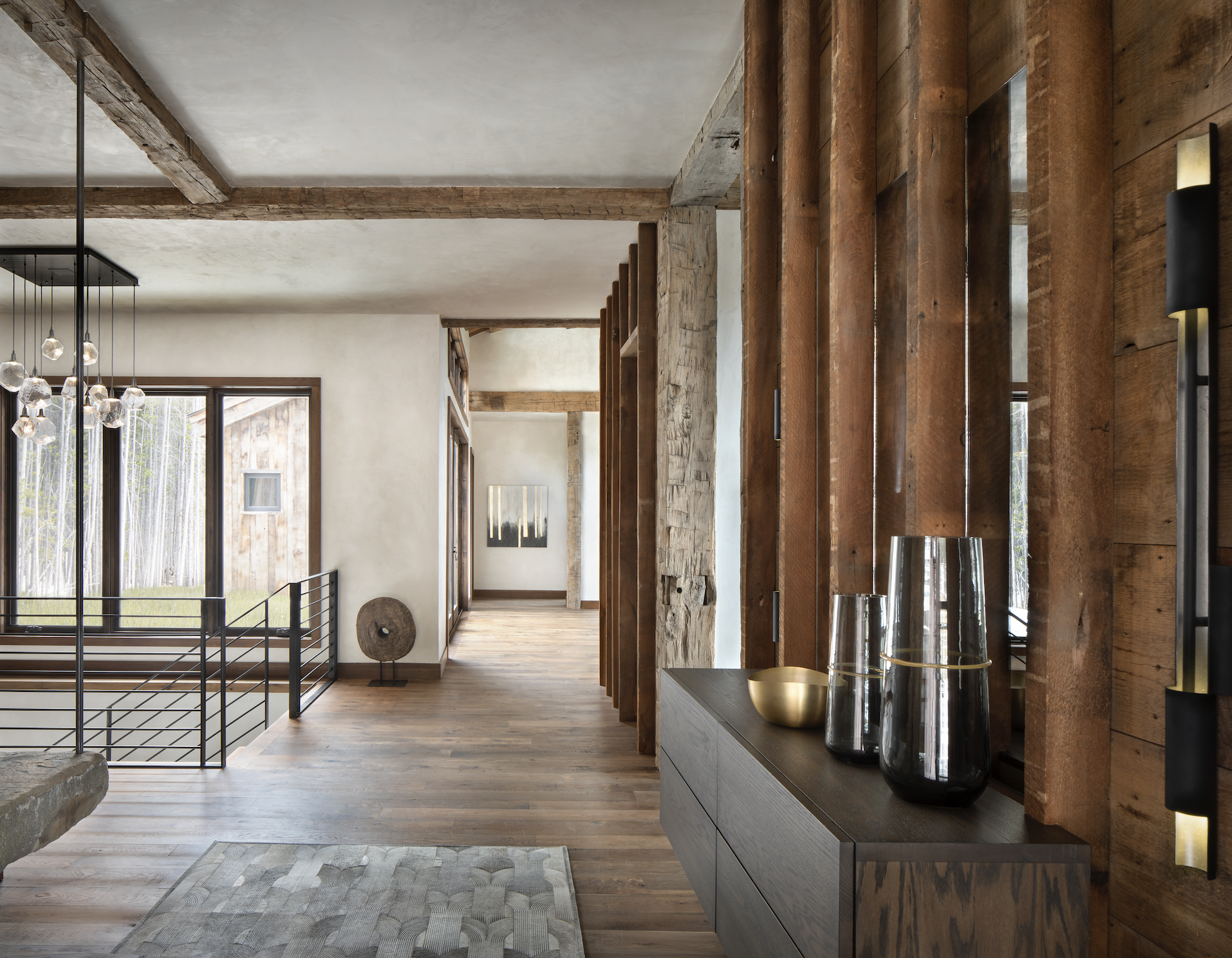 Upper-level hallway with reclaimed timber wall detailing, stone accents, and steel railing.