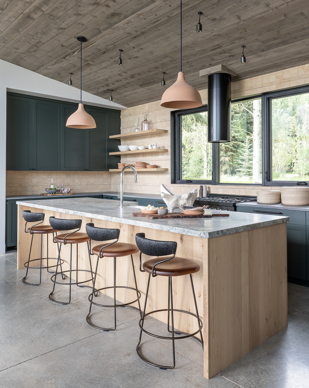 Kitchen with wood island, stone countertop, and pendant lighting with Montana forest out the window