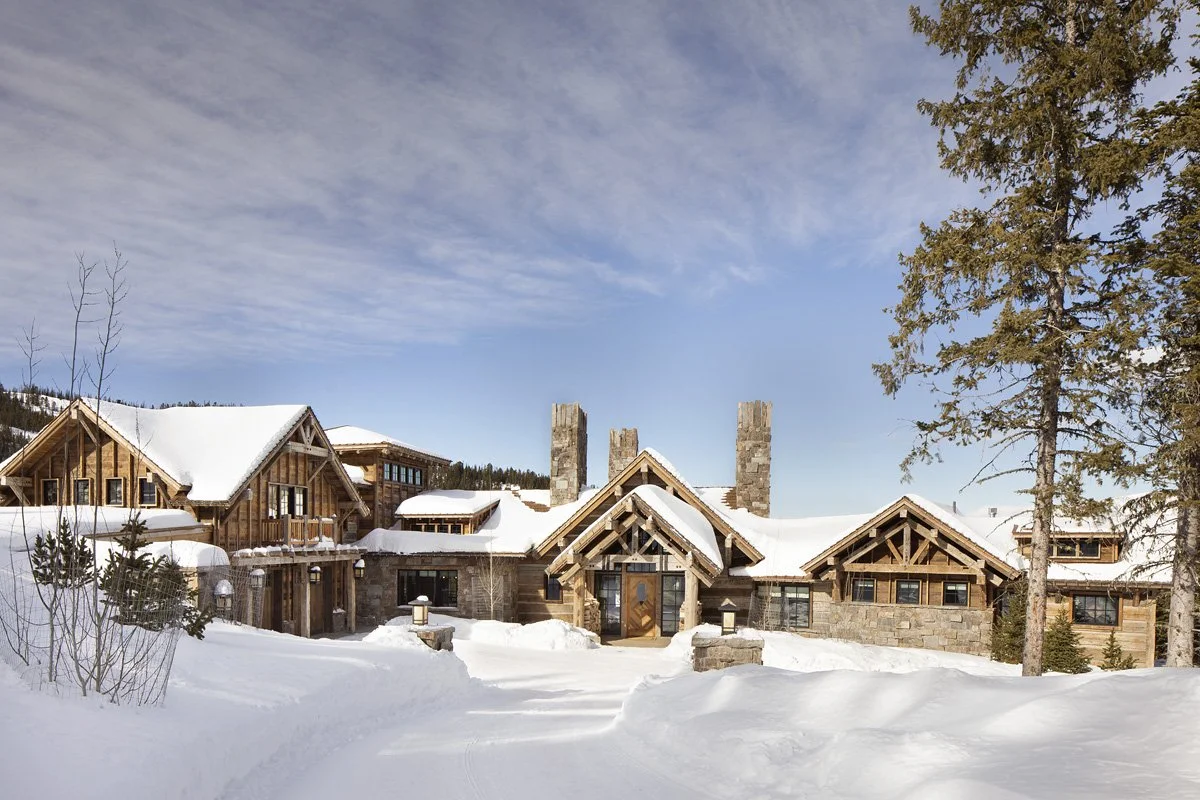Full property view of mountain lodge with multiple structures in snow at Moonlight Basin Big Sky Montana