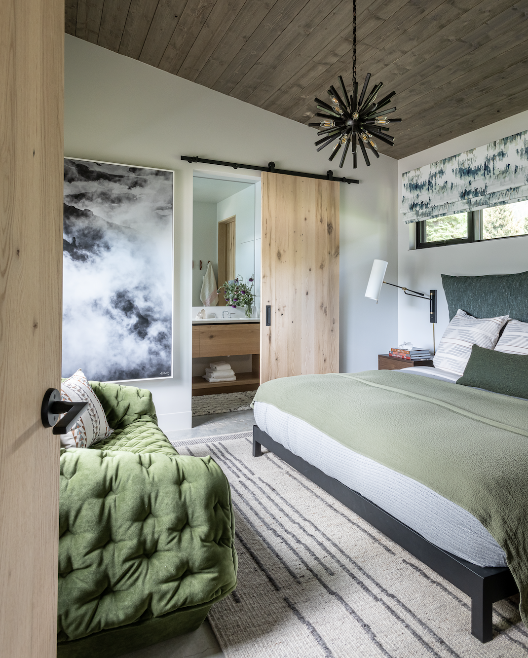Bedroom with green bedding, wood ceiling, sliding barn door and modern lighting