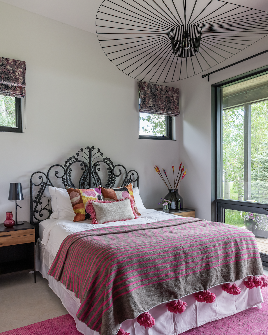 Bedroom with metal bed frame, pink textiles, and large windows