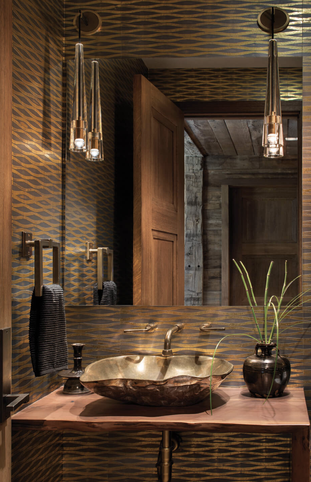 Powder bathroom with bronze vessel sink, custom wood vanity, patterned wallcovering, and contemporary pendant lighting.