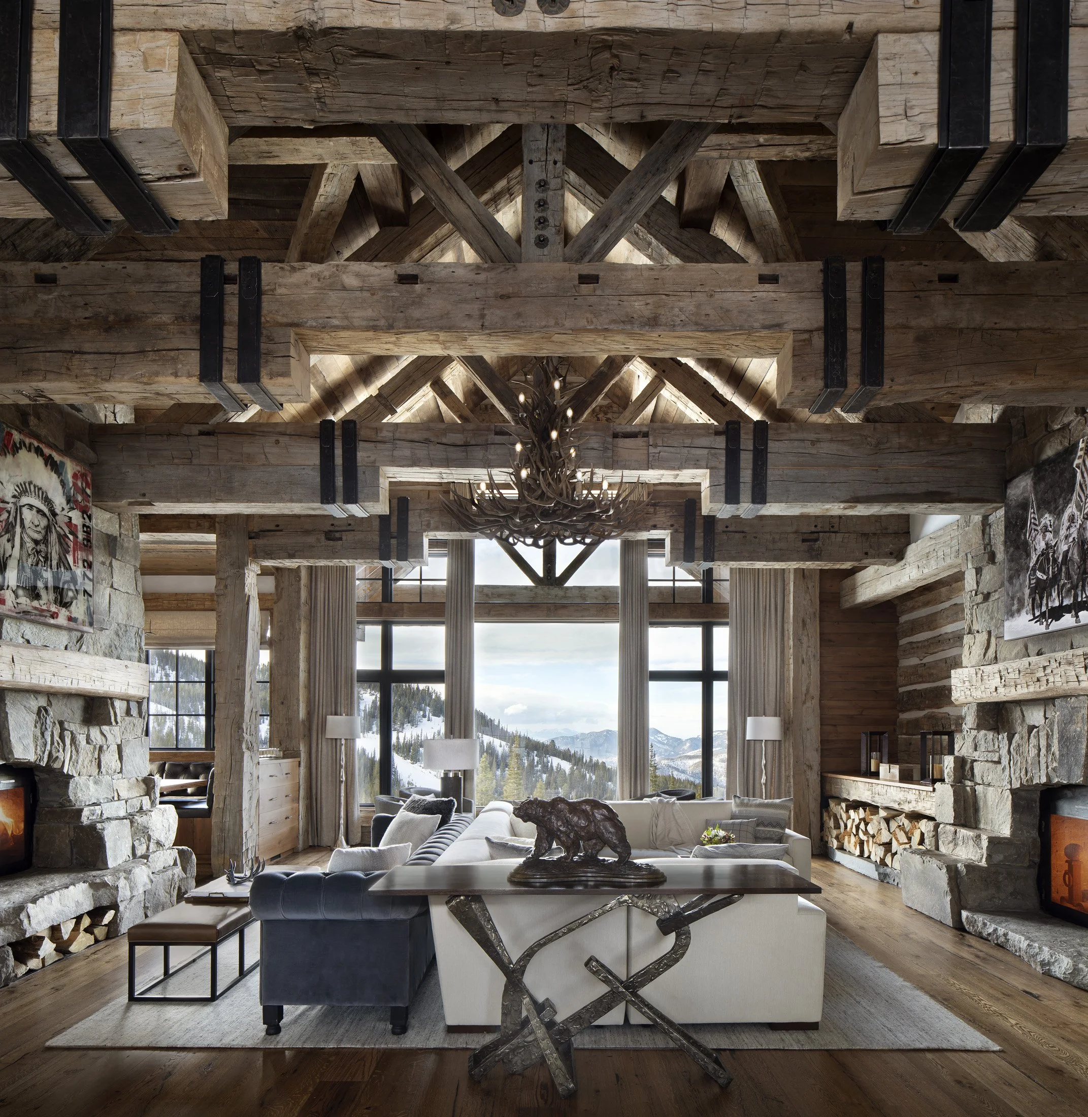 Great room with exposed timber structure, stone fireplace, and large windows at Big Sky Montana