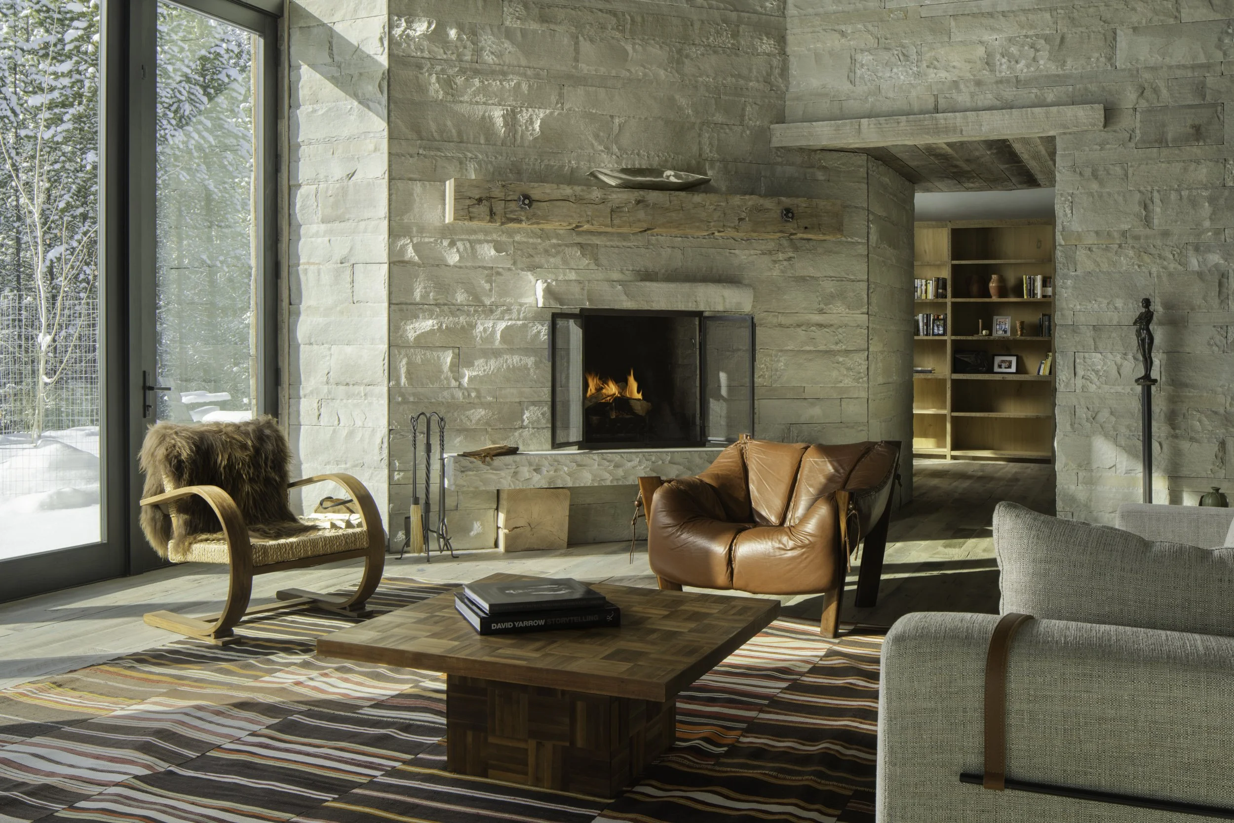 Living room with stone fireplace wood ceiling and open layout in Big Sky Montana