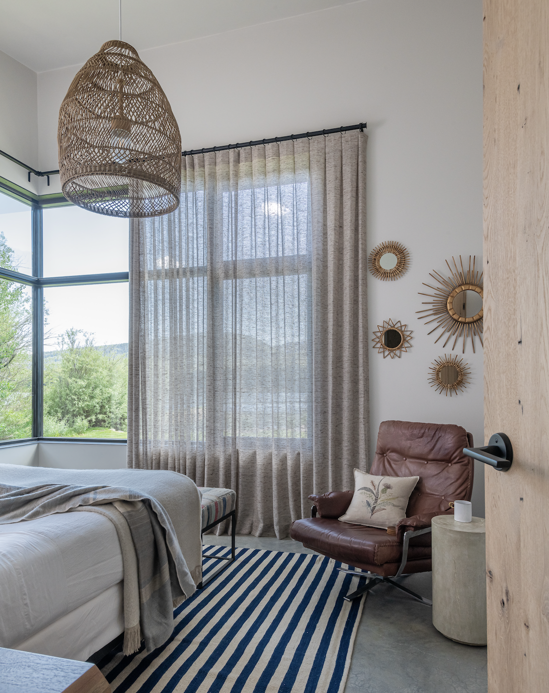 Bedroom with neutral tones, window seating, and woven pendant light with lake views
