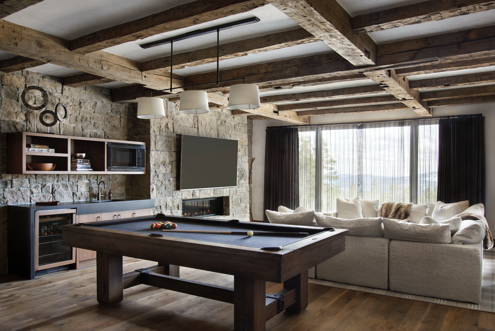 Recreation room with billiards table, stone fireplace, built-in bar, and mountain views.